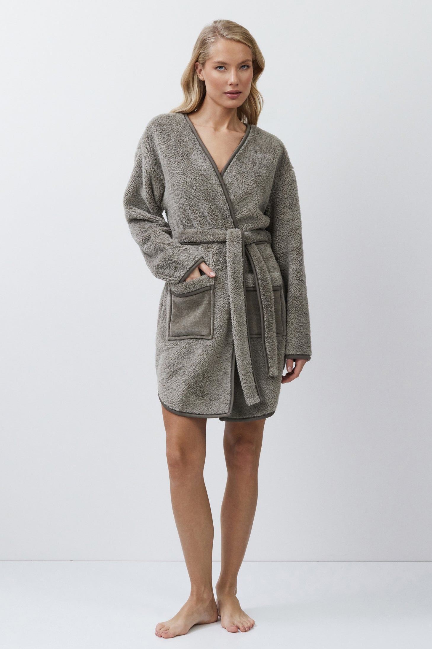 Woman wearing a gray bathrobe on a white background