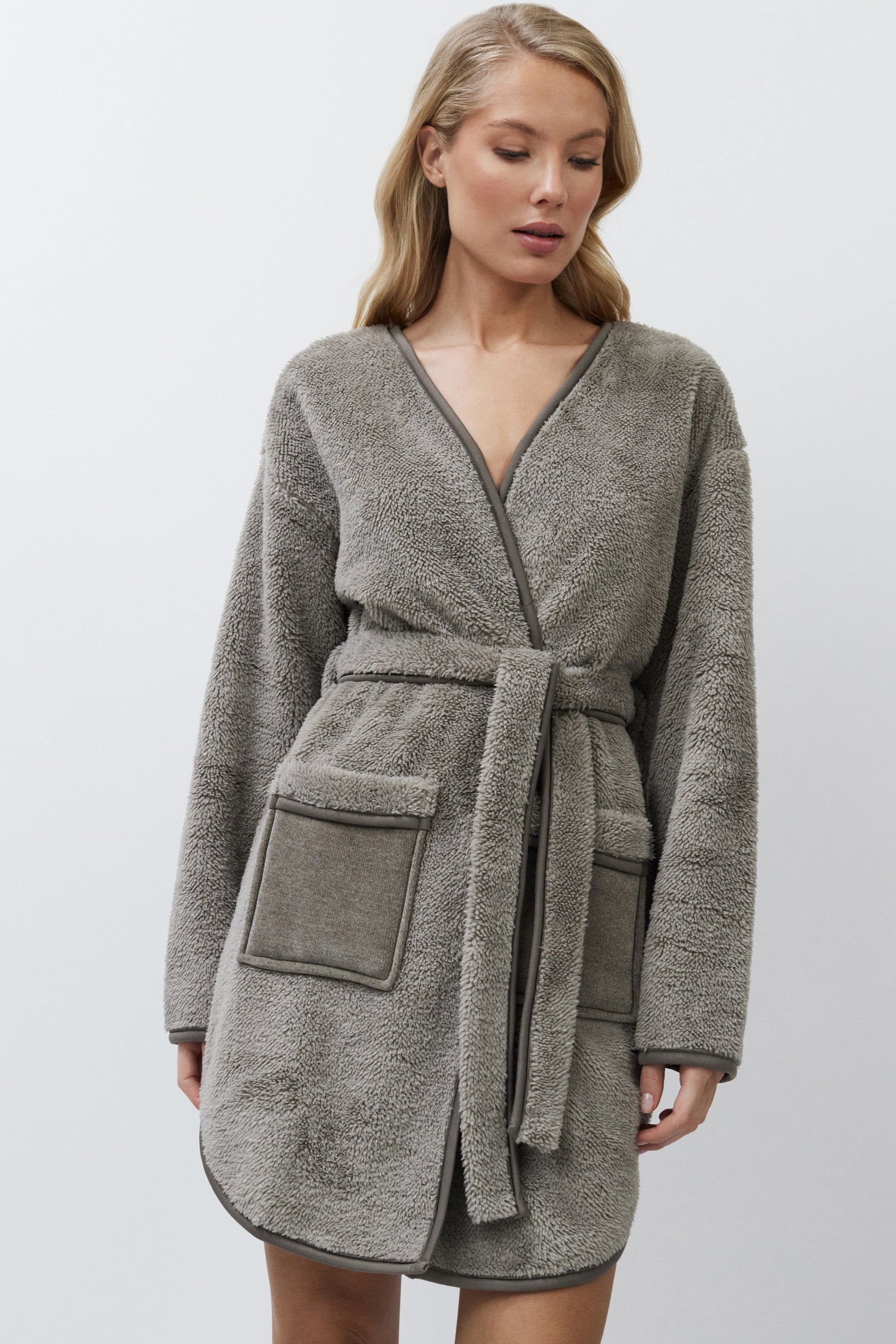 Woman wearing a gray bathrobe on a white background