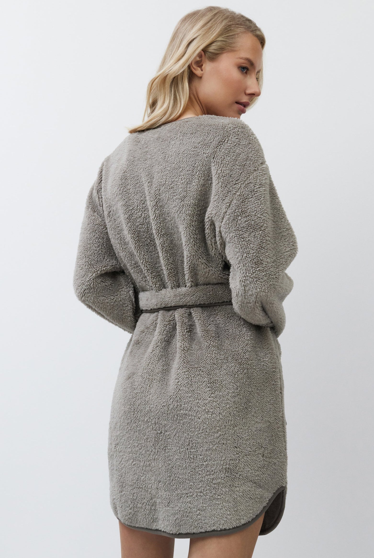 Woman wearing a gray textured bathrobe against a white background