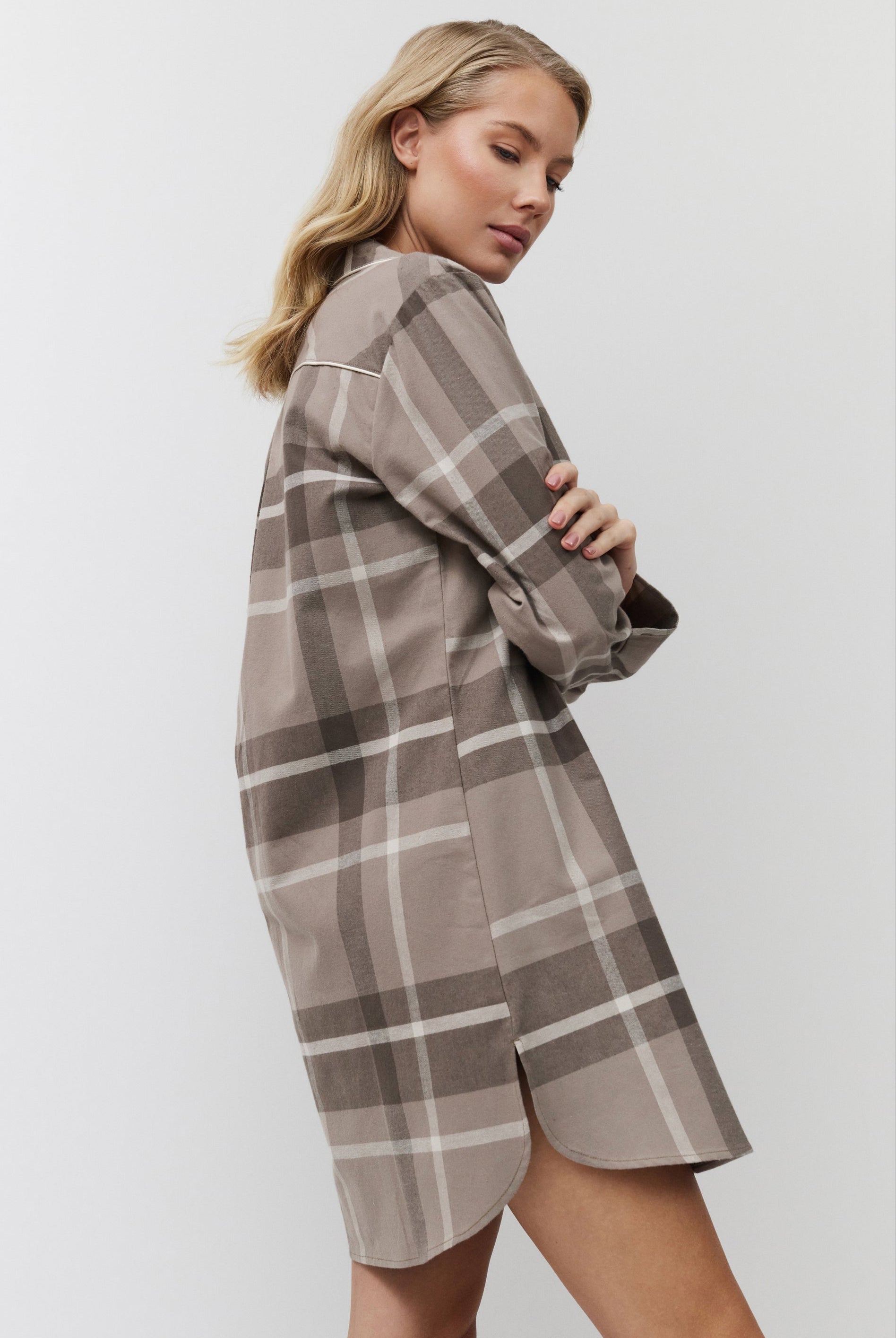 Woman wearing a plaid nightdress against a plain background