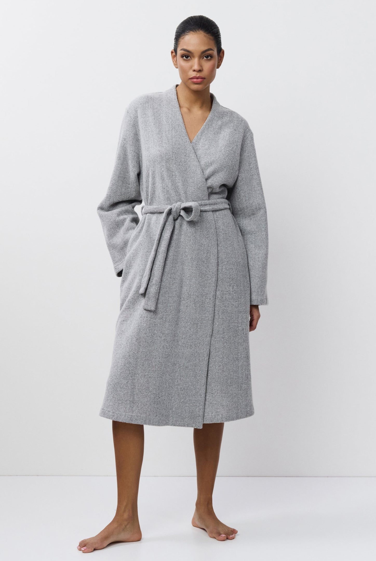 Woman wearing a gray bathrobe against a white background
