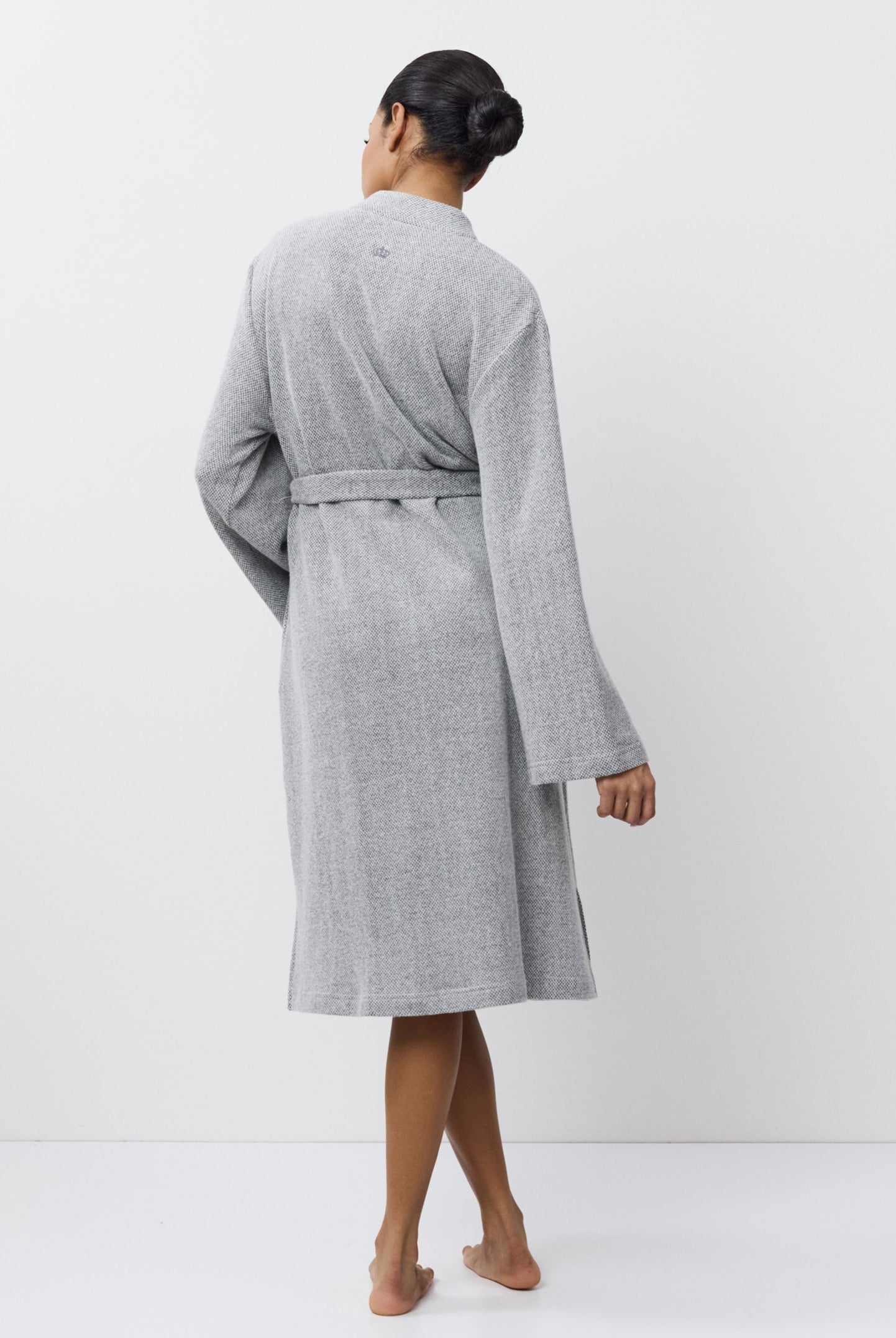 Person wearing a gray bathrobe against a white background