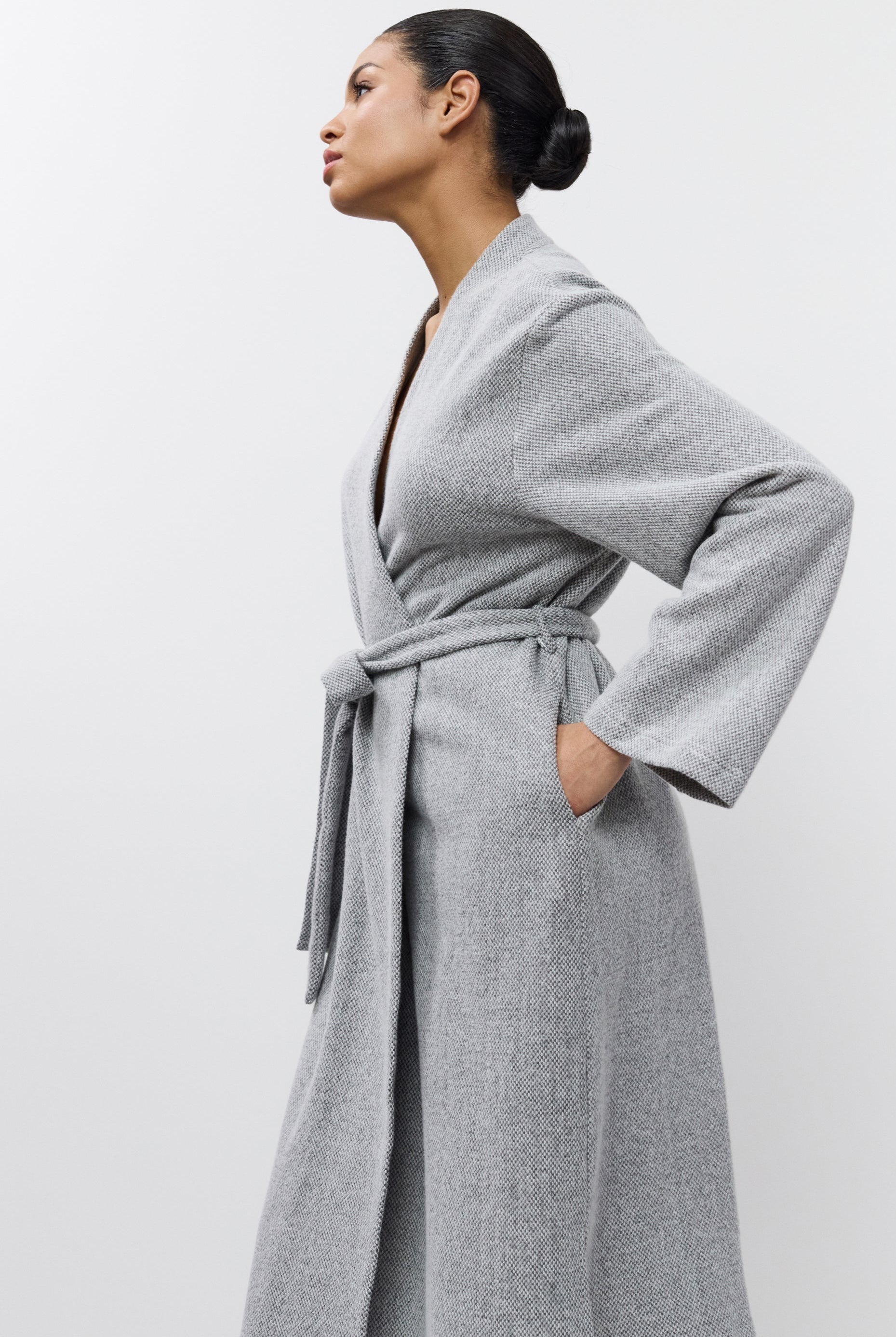 Woman wearing a gray bathrobe against a white background