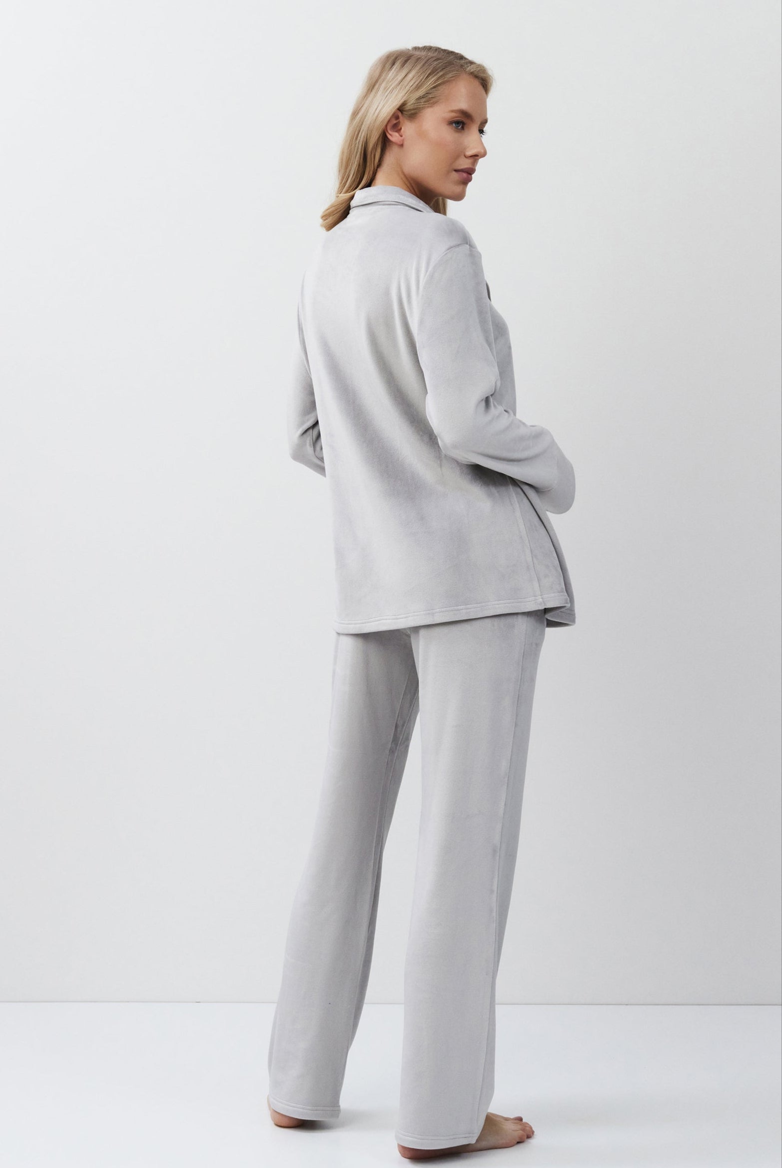 Woman wearing a light gray set standing against a white background