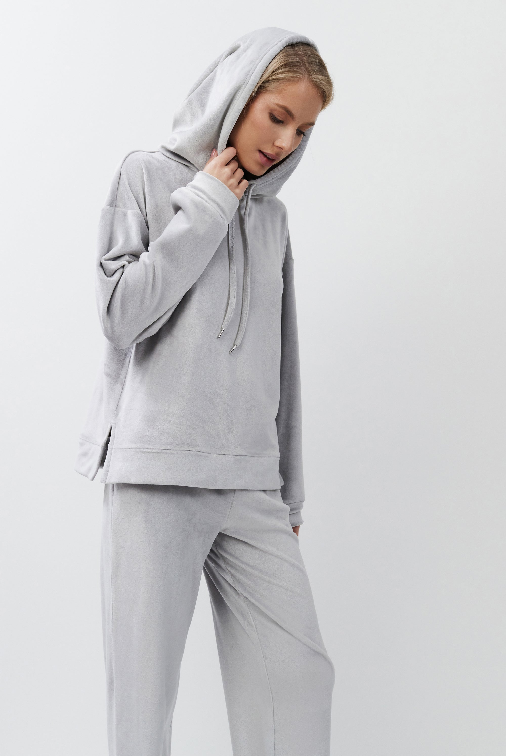 Person wearing a gray hoodie and pants on a white background