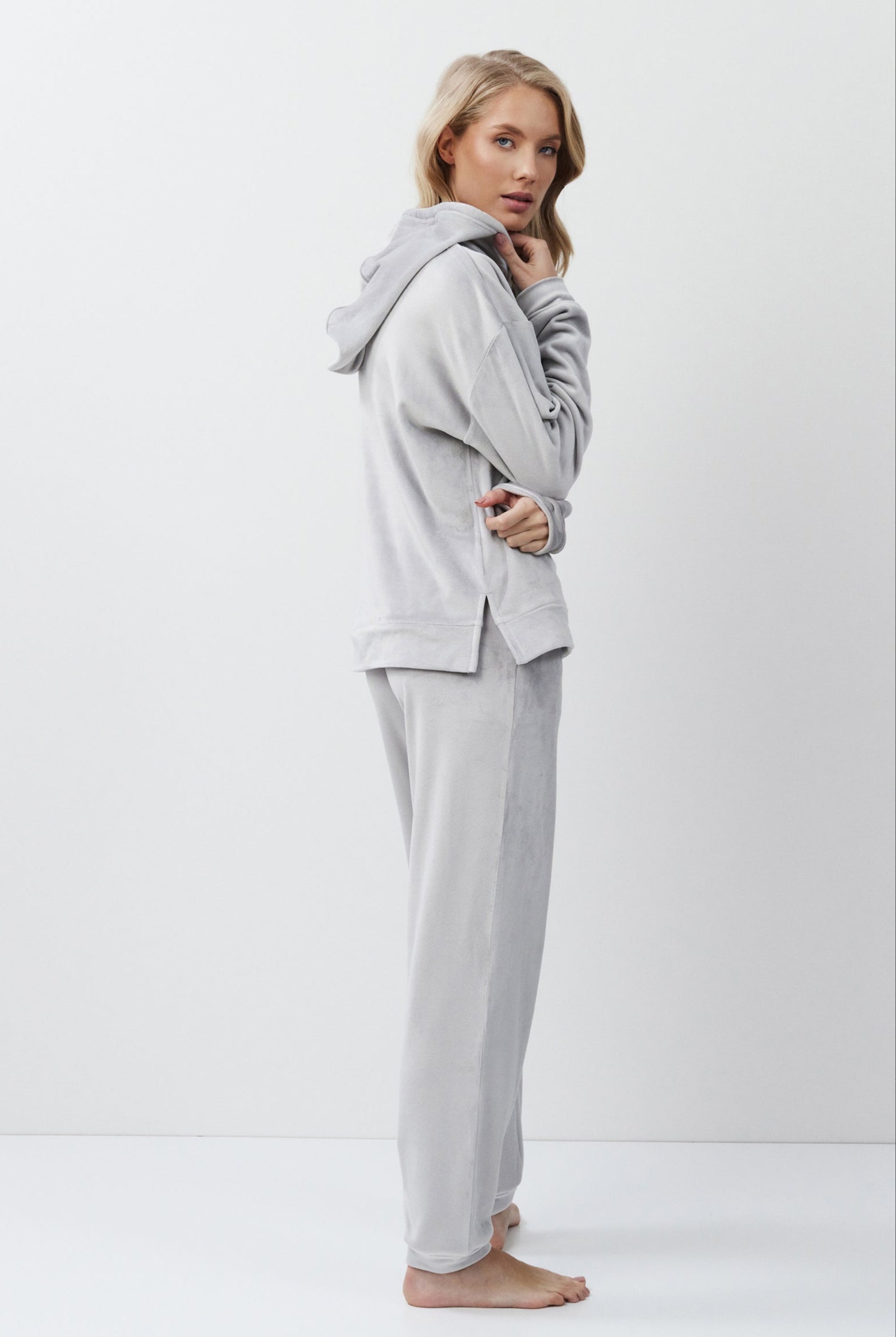 Woman wearing a gray hoodie and pants on a white background