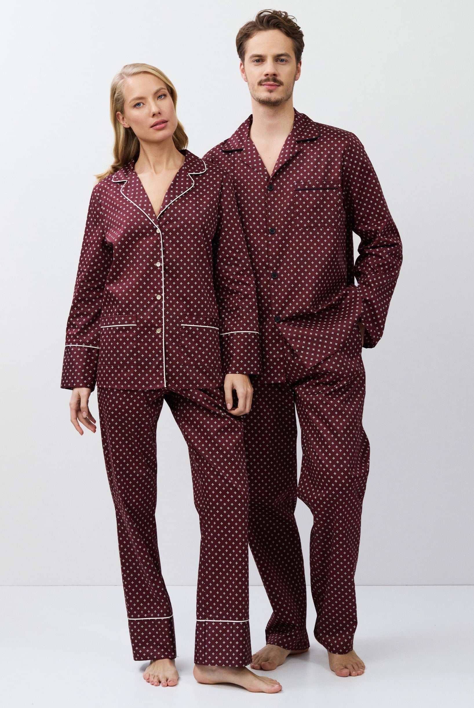 Two people wearing matching burgundy pajamas on a white background