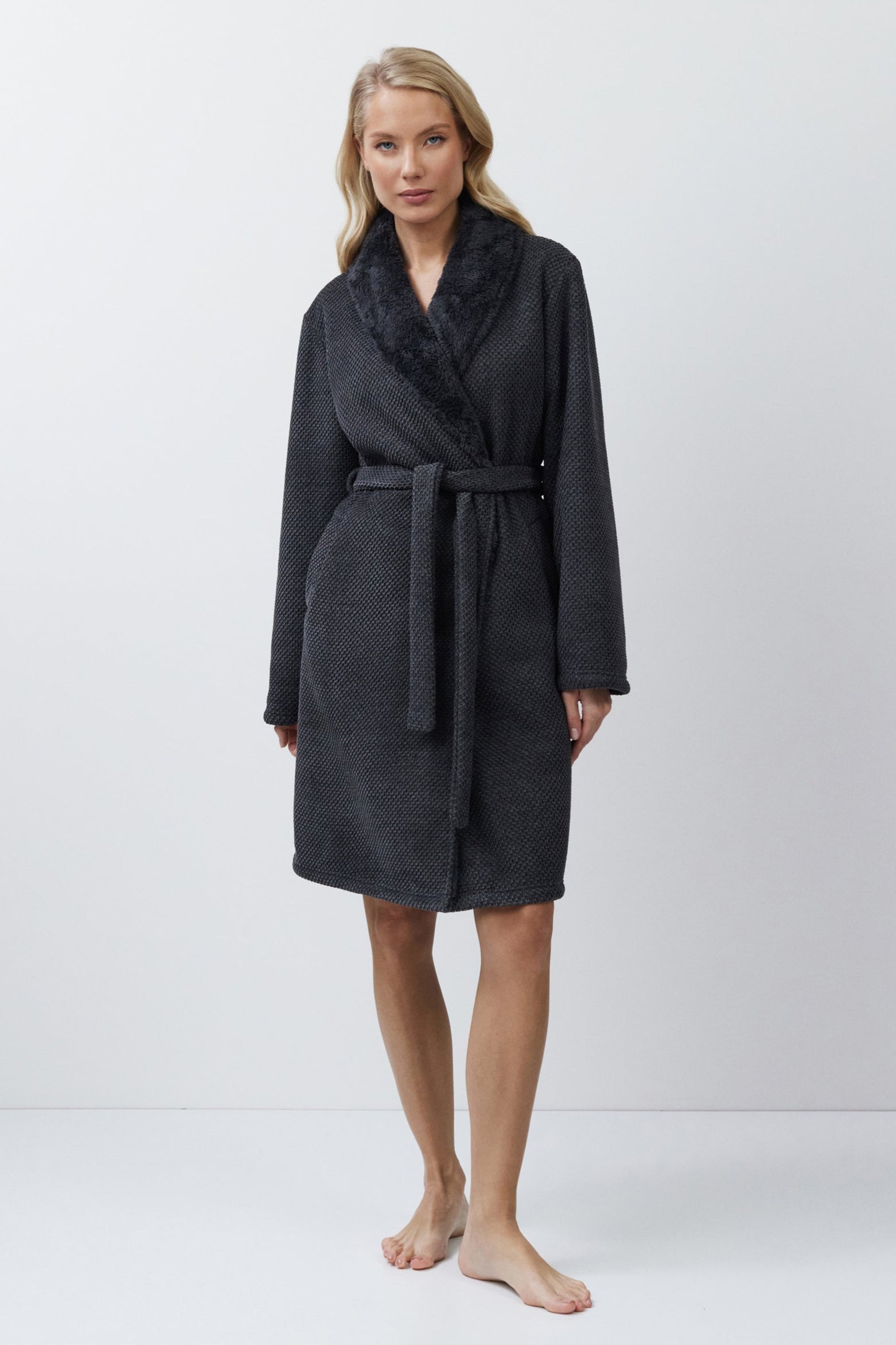 Woman wearing a gray bathrobe on a white background