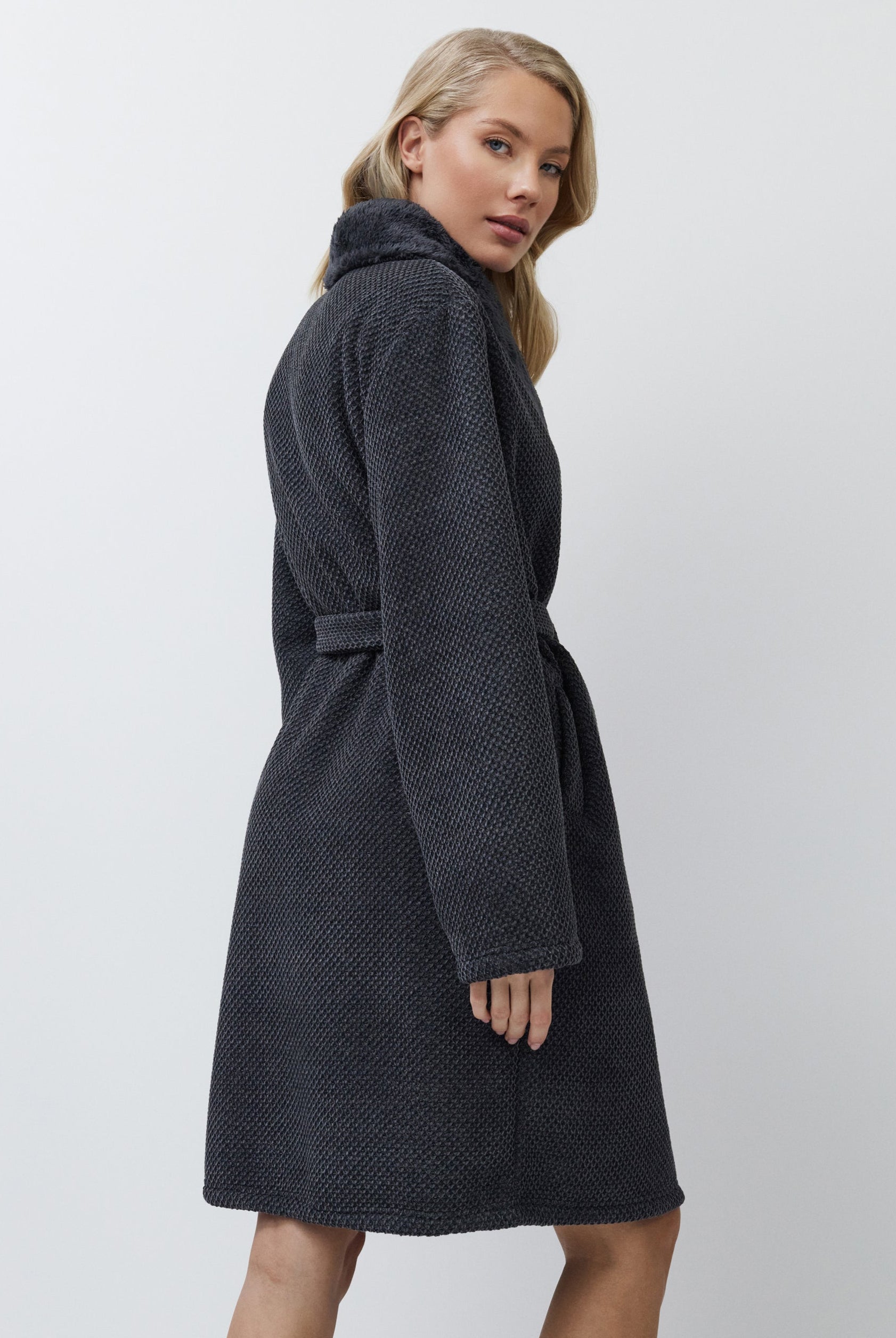 Woman wearing a dark gray textured bathrobe on a white background