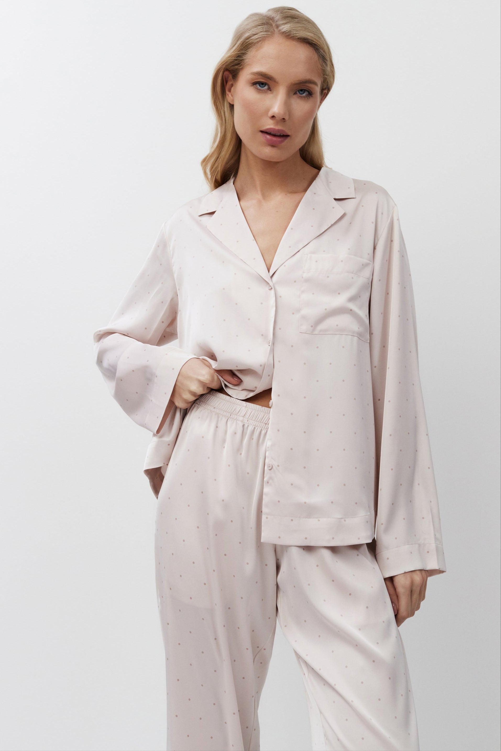 Woman wearing a light pink pajama set against a white background