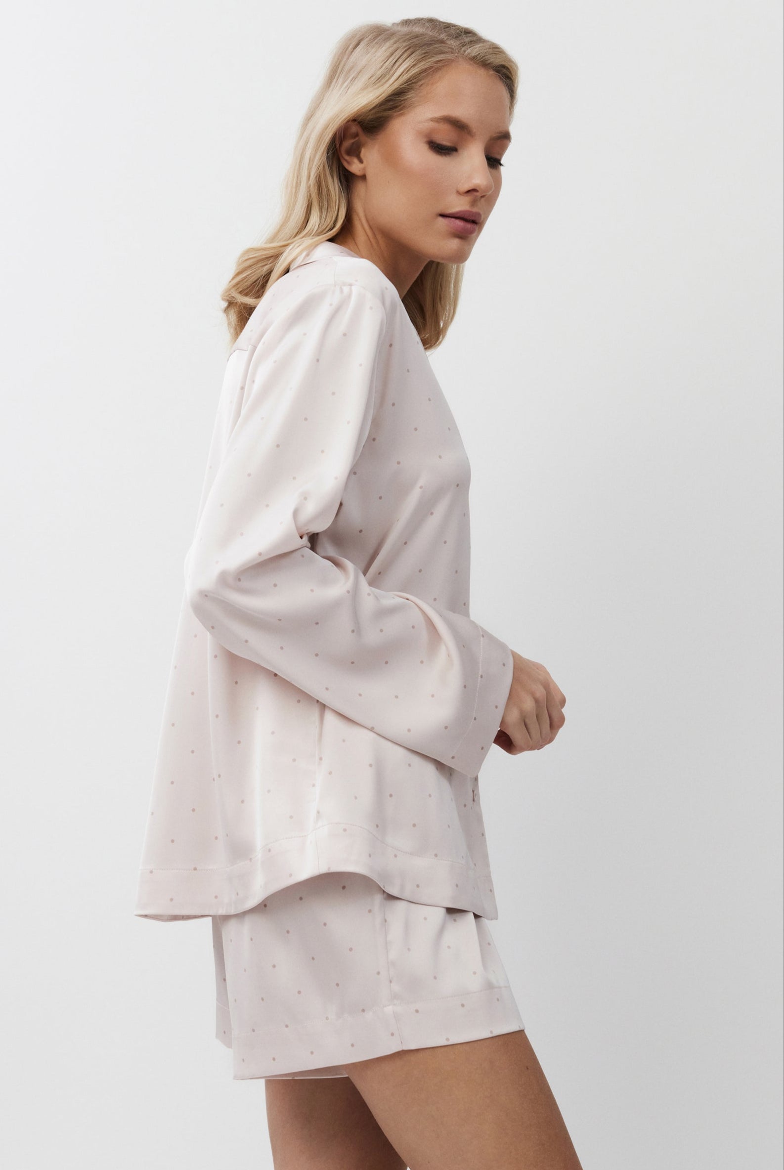 Woman wearing a light pink pajama set on a white background