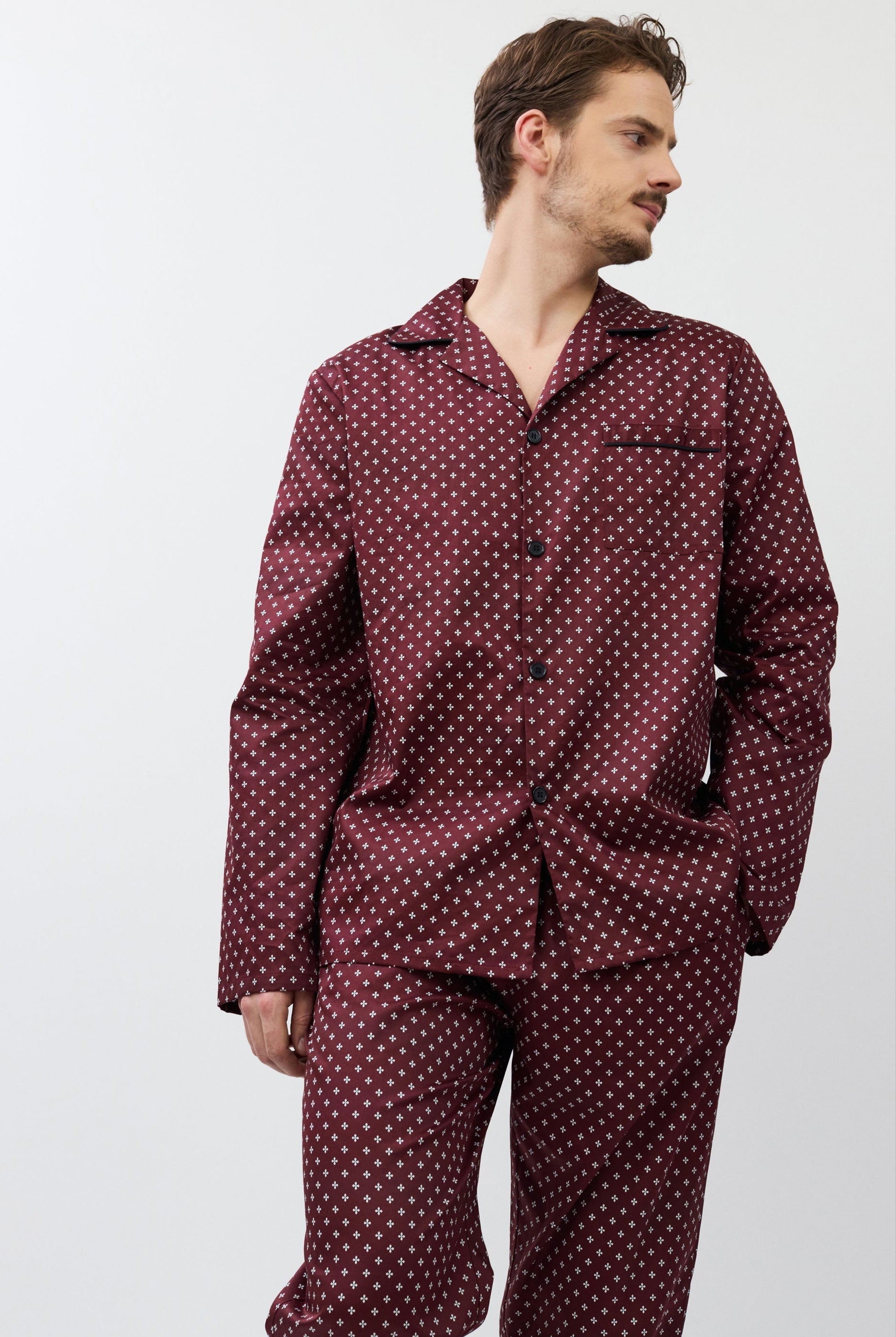 Man wearing a burgundy patterned pajama set against a white background