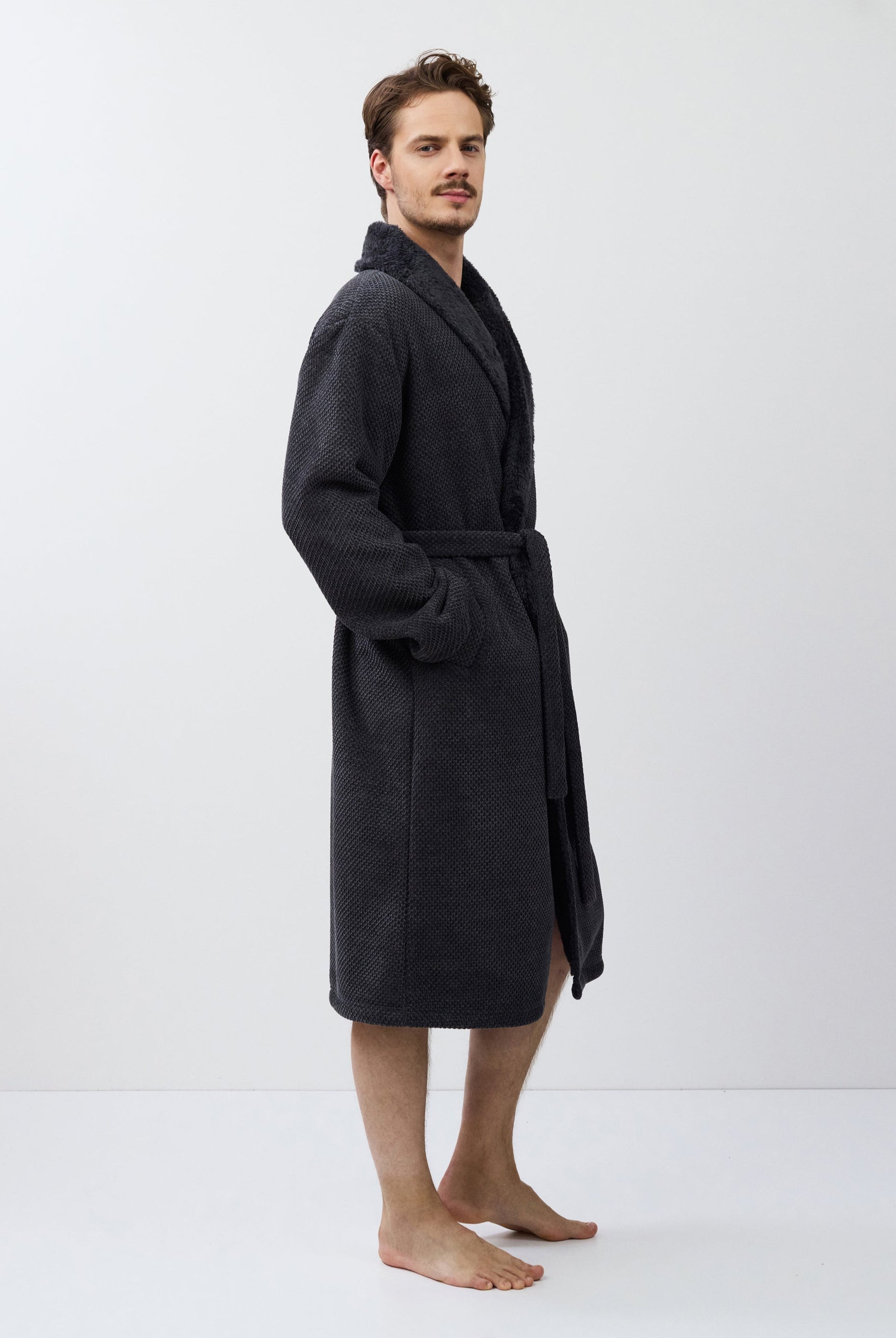 Man wearing a dark gray bathrobe on a white background