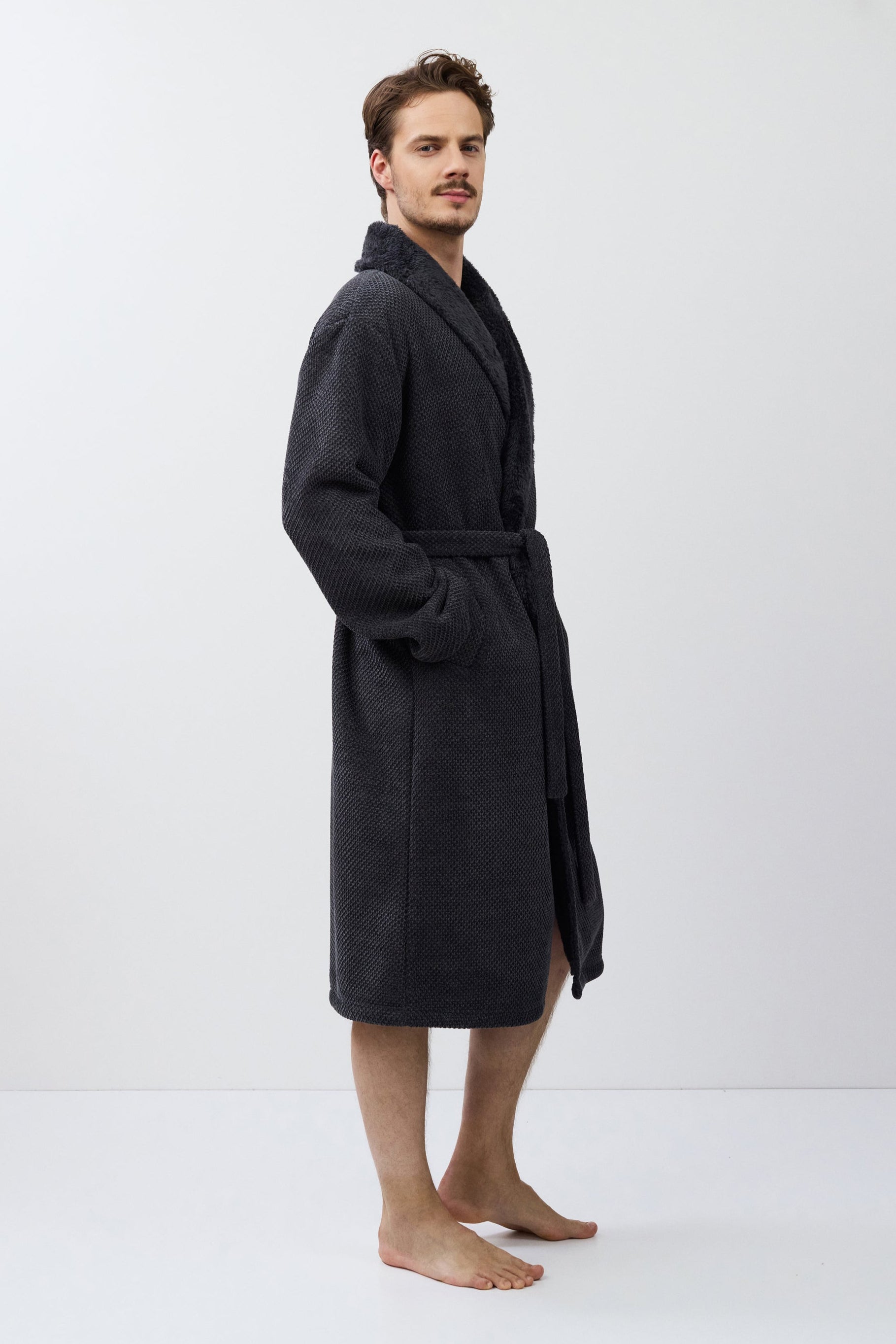 Man wearing a dark gray bathrobe on a white background