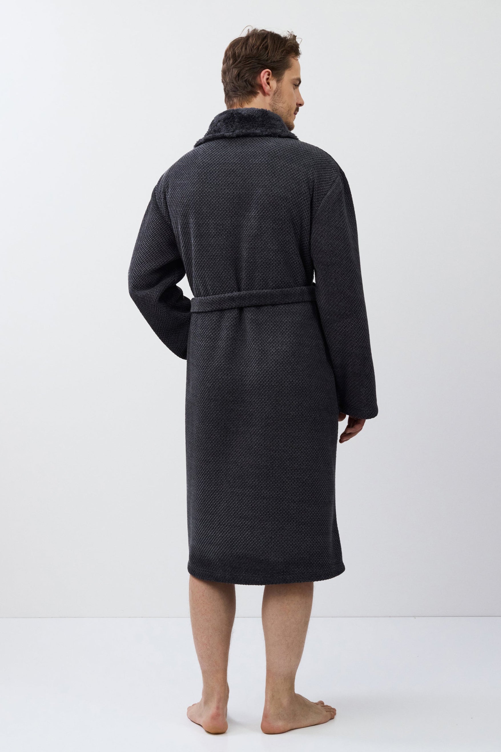 Man wearing a dark gray bathrobe on a white background