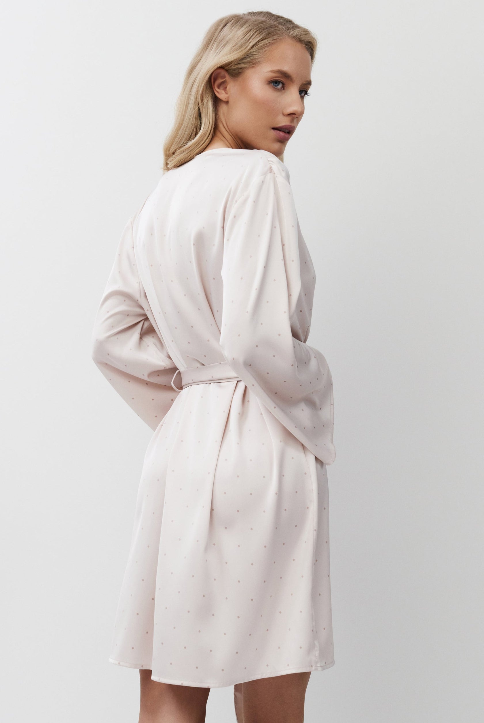 Woman wearing a pink gown against a plain background