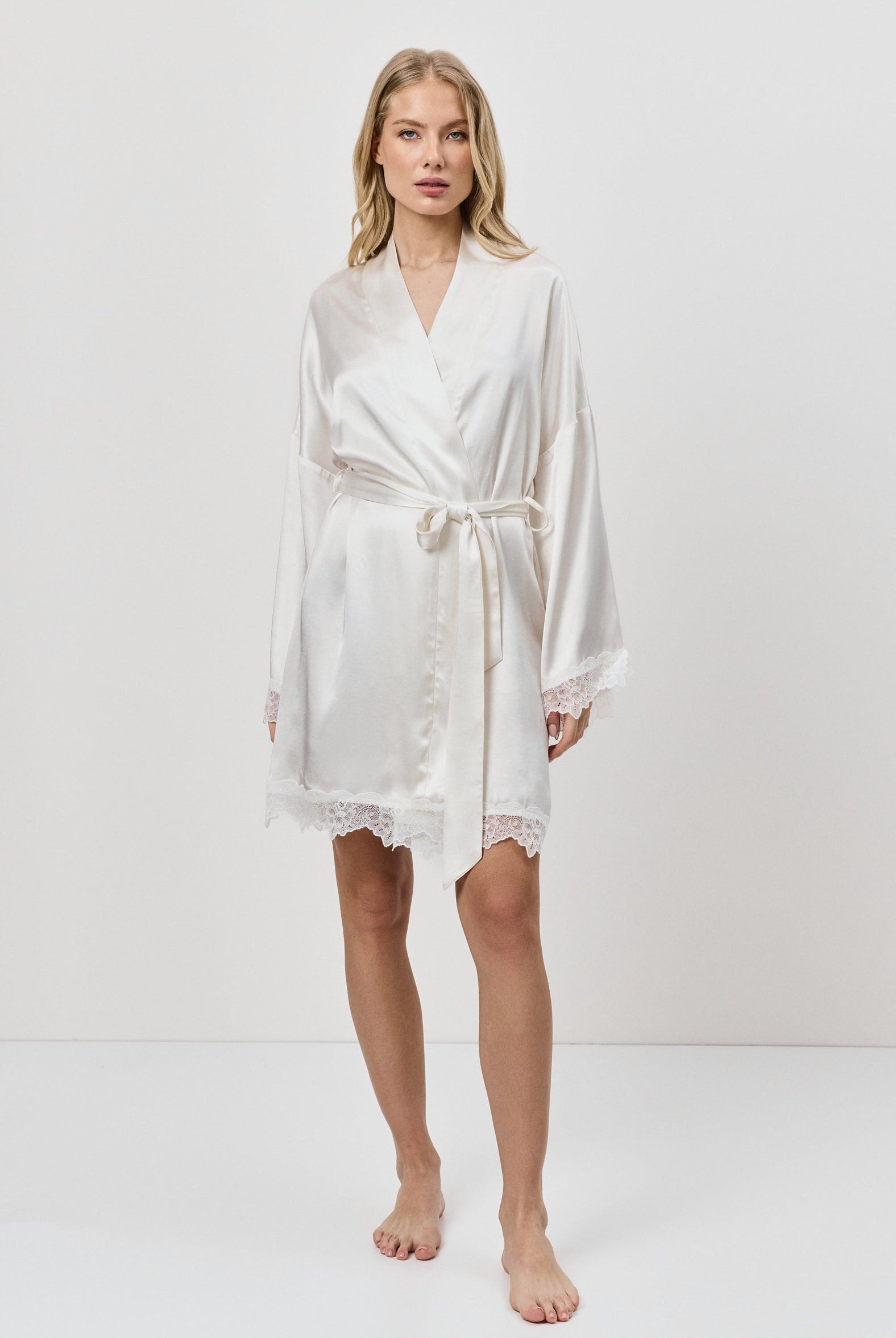 Woman wearing a white gown against a plain background