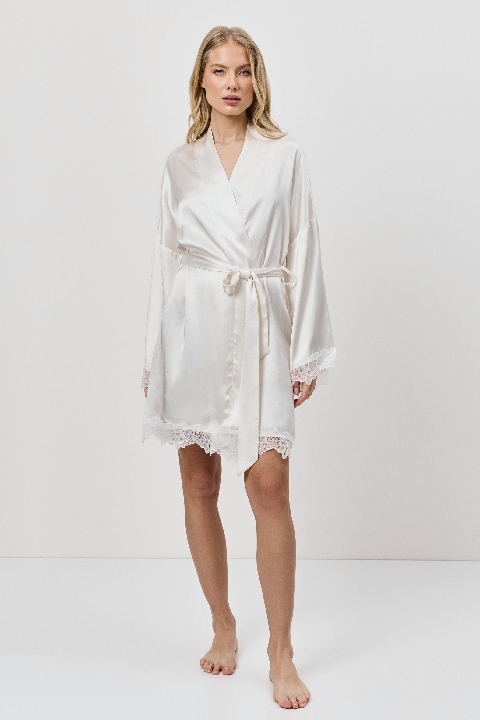 Woman wearing a white gown against a plain background