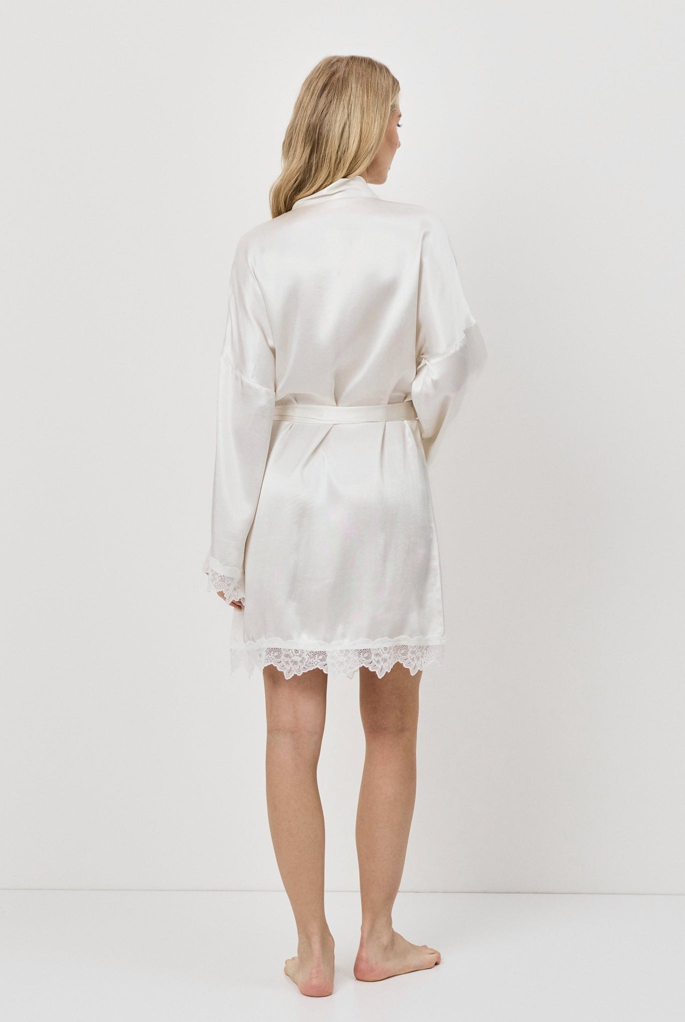 Person wearing a white gown against a plain background