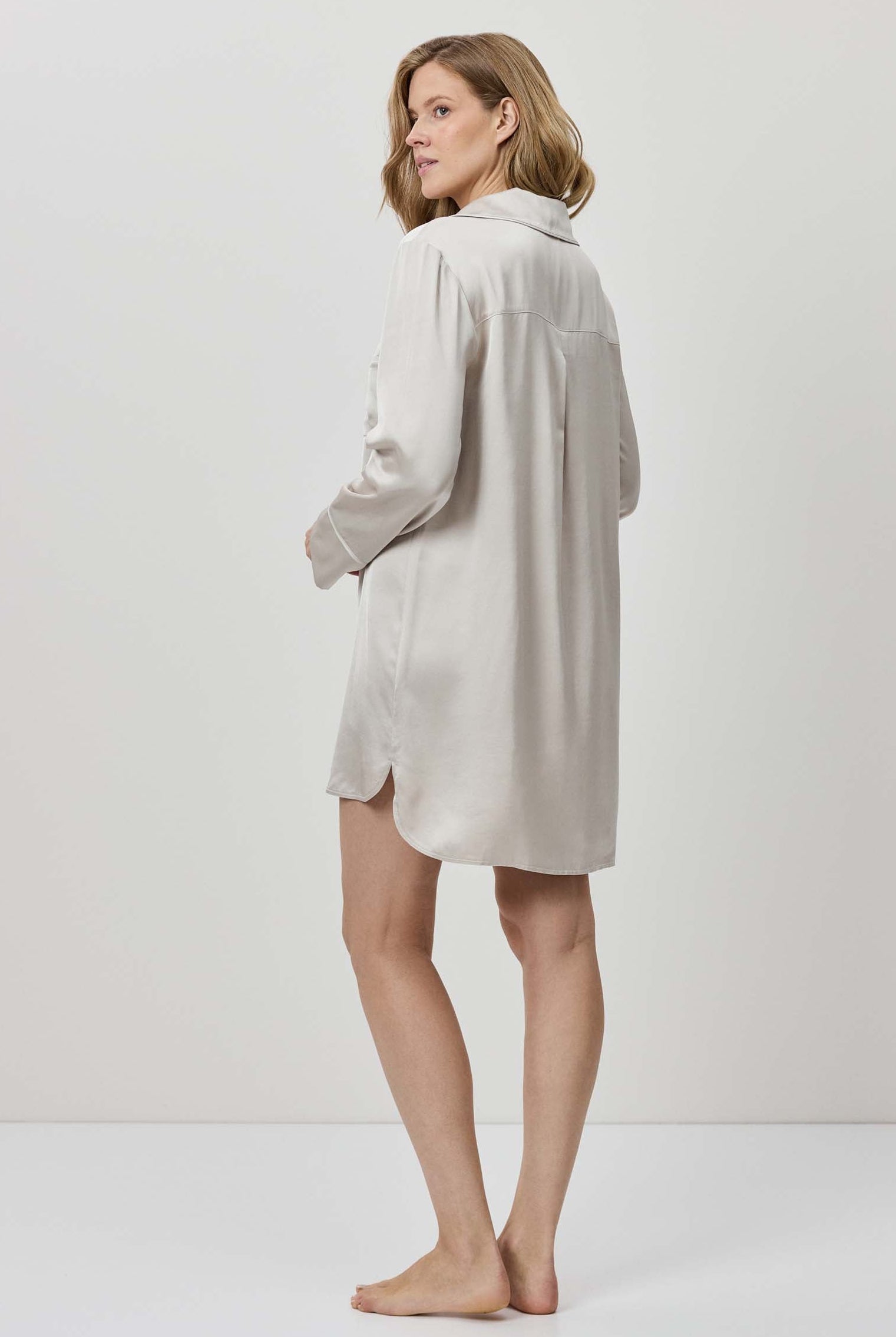 Woman wearing a light gray dress against a white background