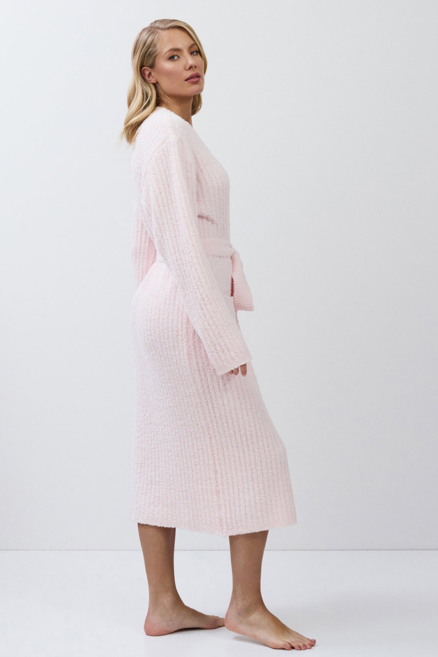 Woman wearing a light pink ribbed bathrobe on a white background