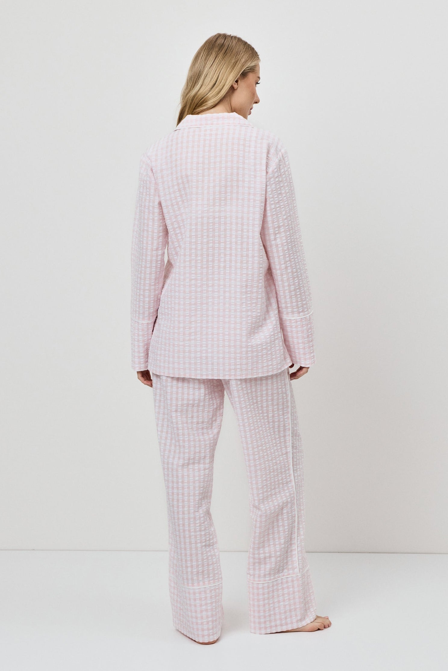 Woman wearing a pink checkered pajama set against a white background