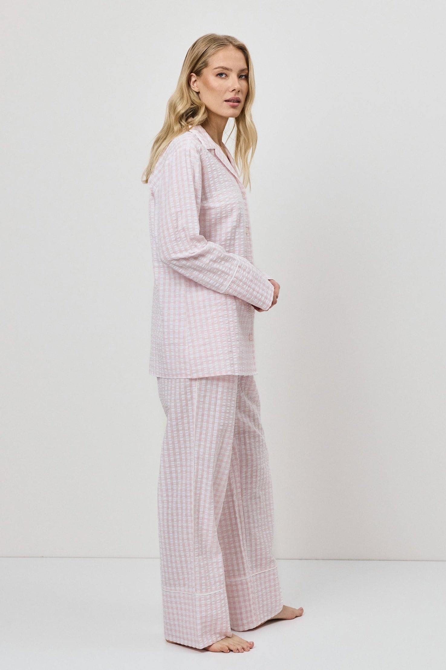 Woman wearing a pink checkered pajama set against a white background