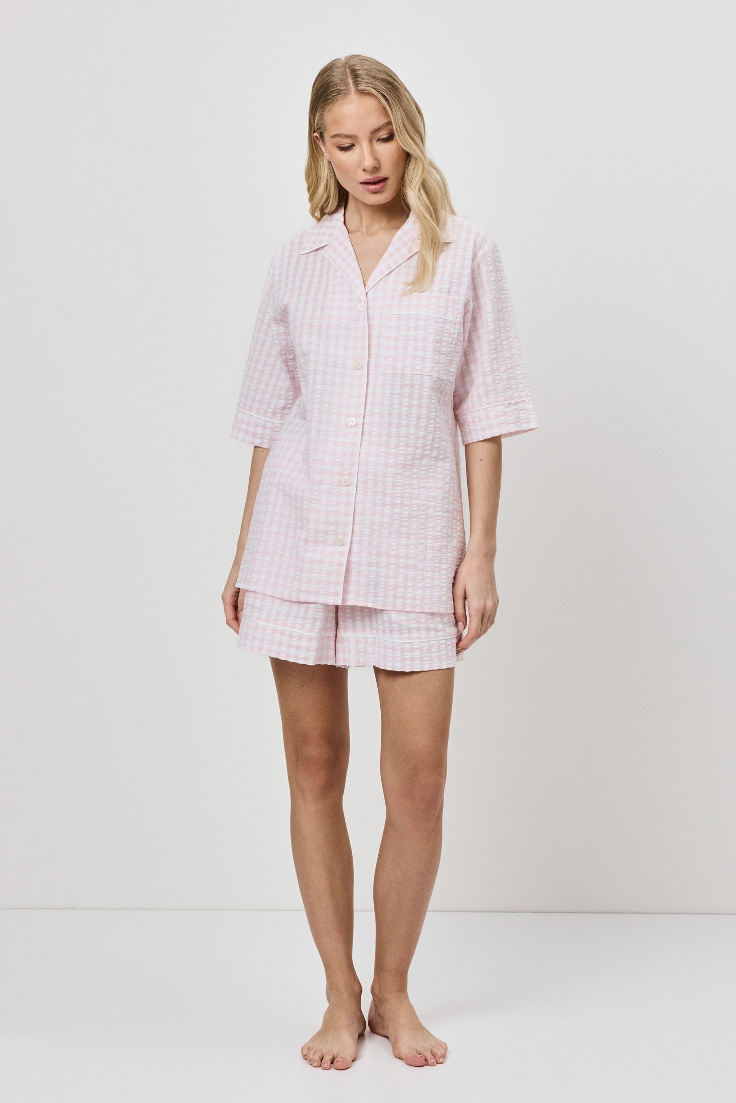 Woman wearing a pink checkered pajama set on a white background