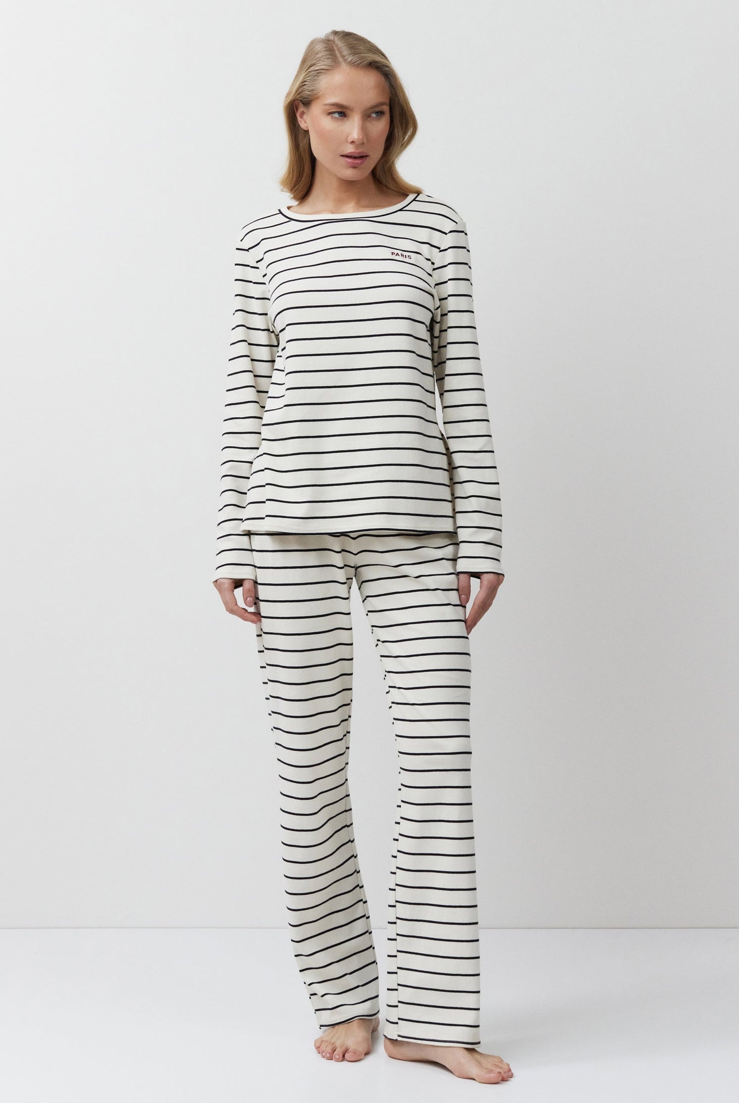 Woman wearing a striped pajama set against a white background