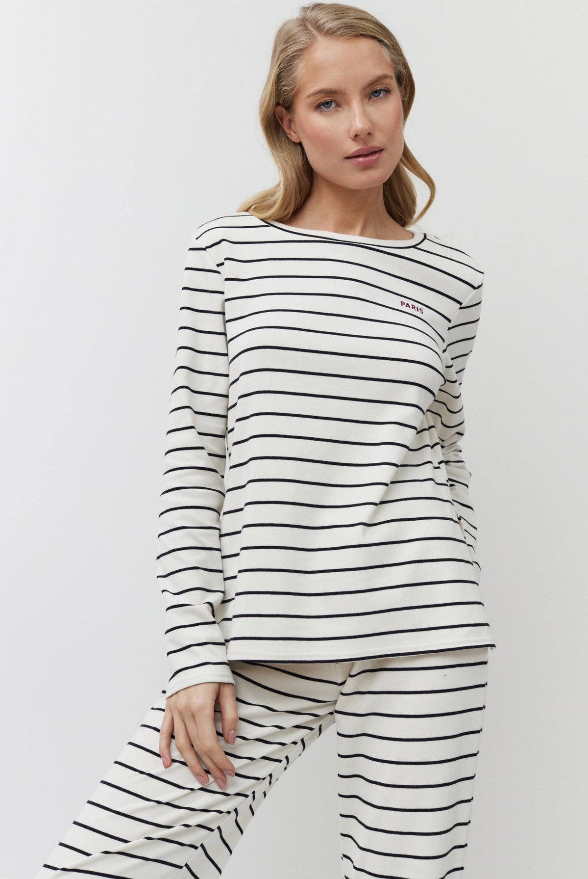 Woman wearing a black and white striped long-sleeve top and pants on a white background