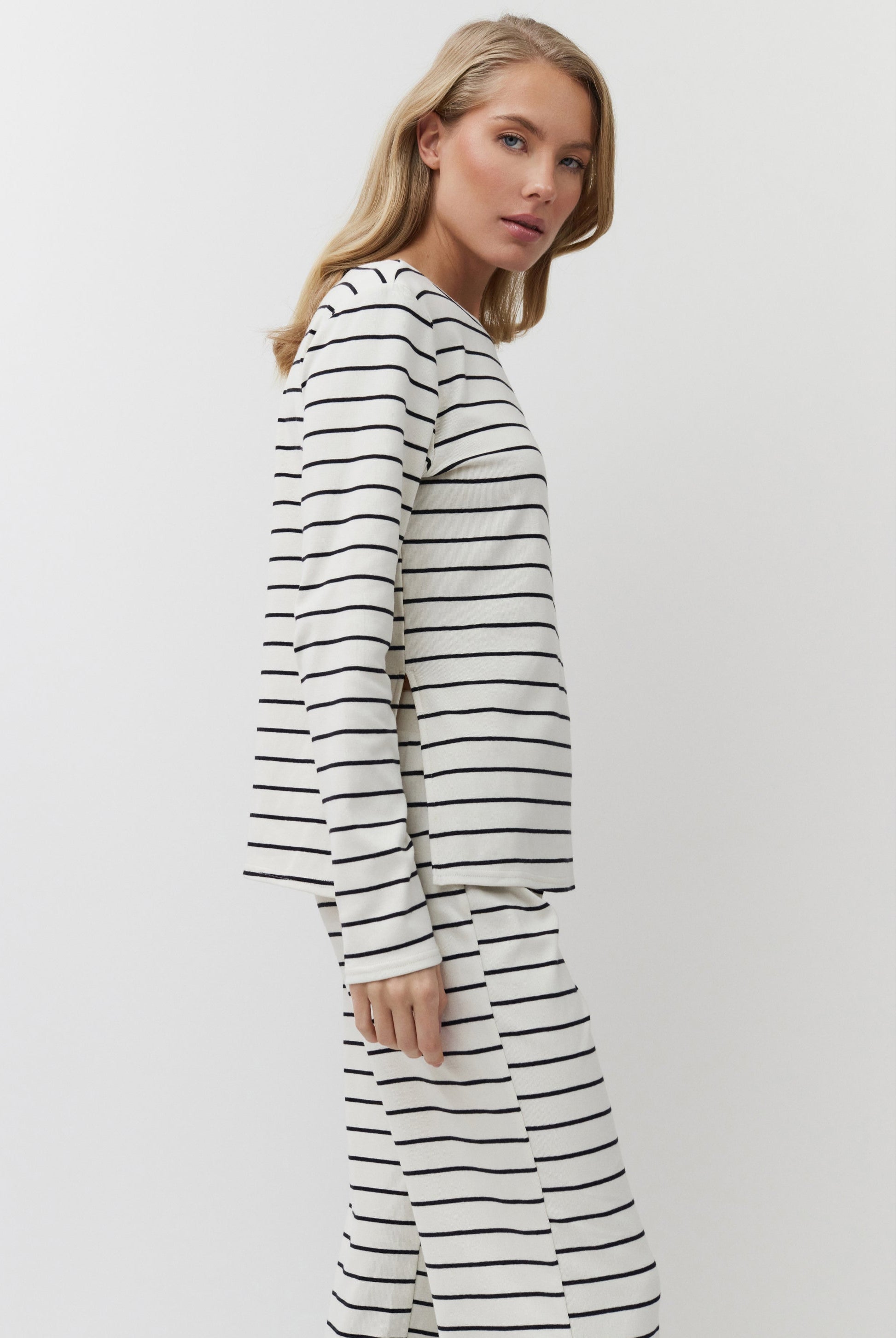 Woman wearing a long-sleeve, black and white striped set against a plain background