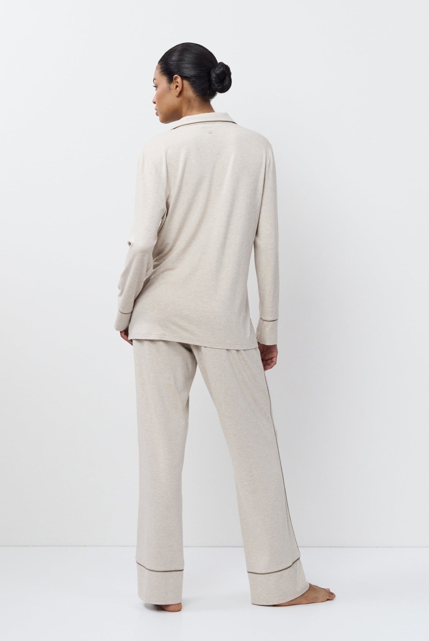 Person wearing a beige set standing against a white background