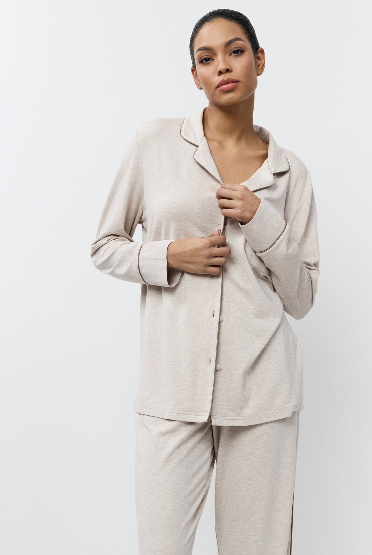 Woman wearing beige pajama set against a white background