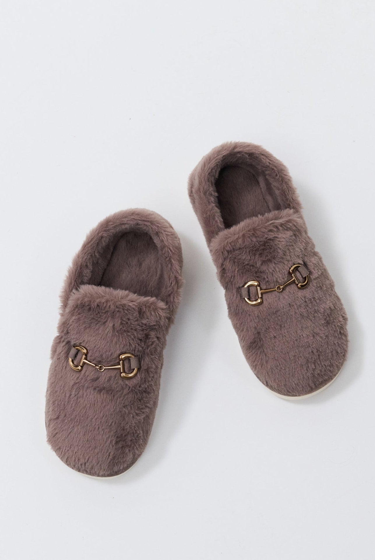Pair of brown slippers with a decorative buckle on a light gray background