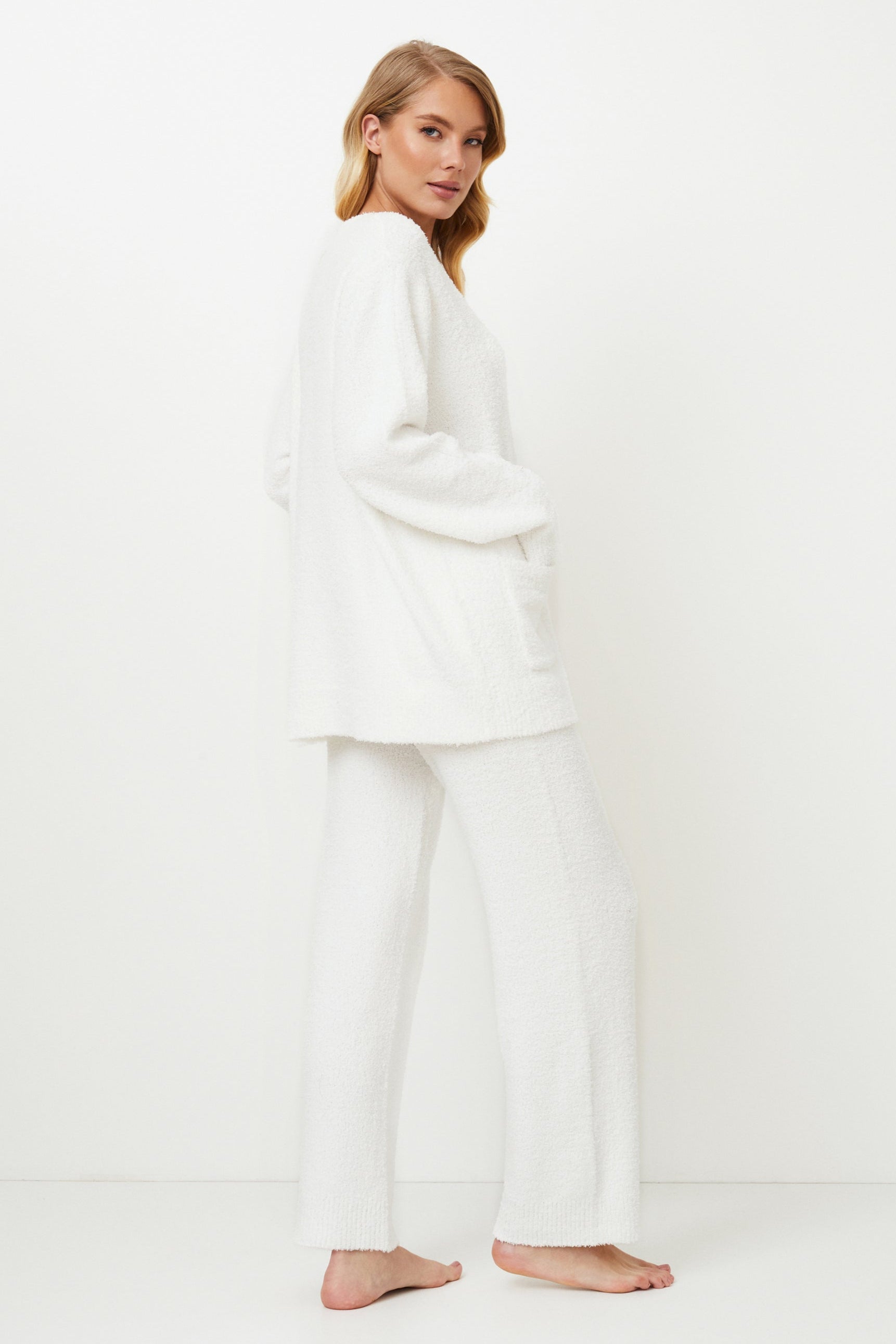 Woman wearing a white homewear set against a white background