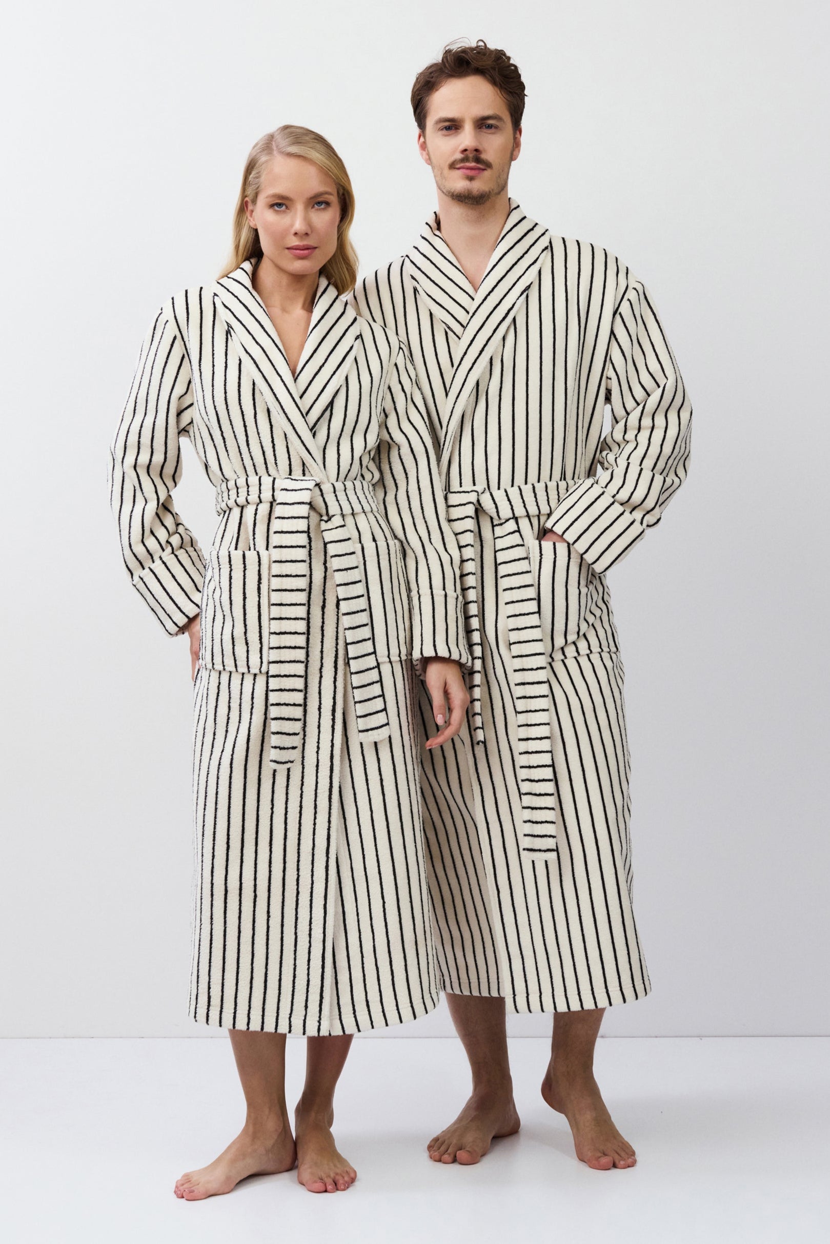 Two people wearing matching striped bathrobes on a white background