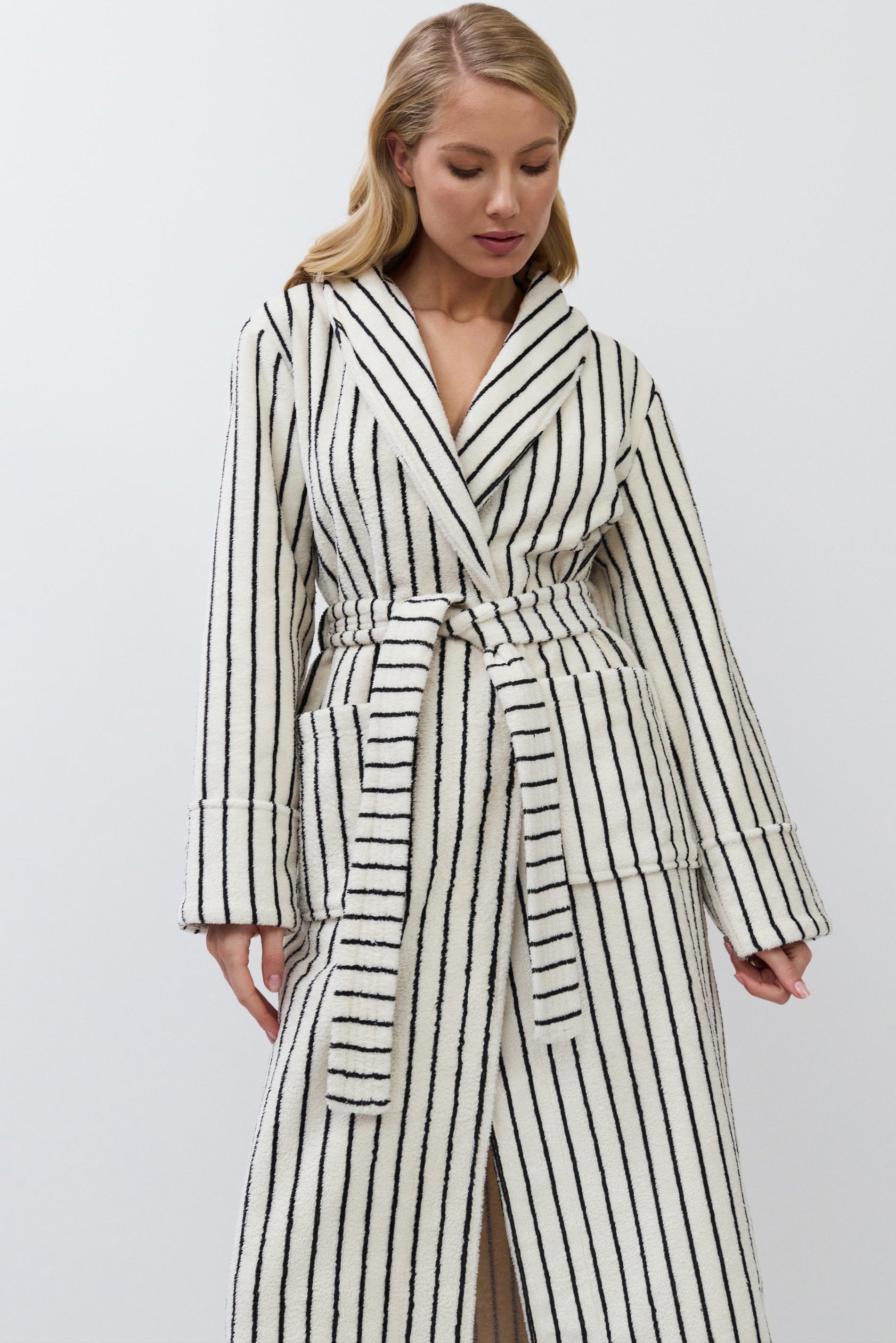 Woman wearing a long, striped batrobe against a plain background