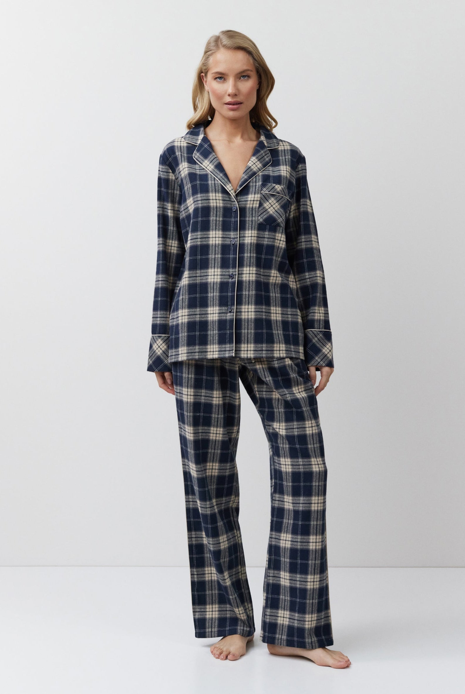 Woman wearing a navy and beige plaid pajama set on a white background