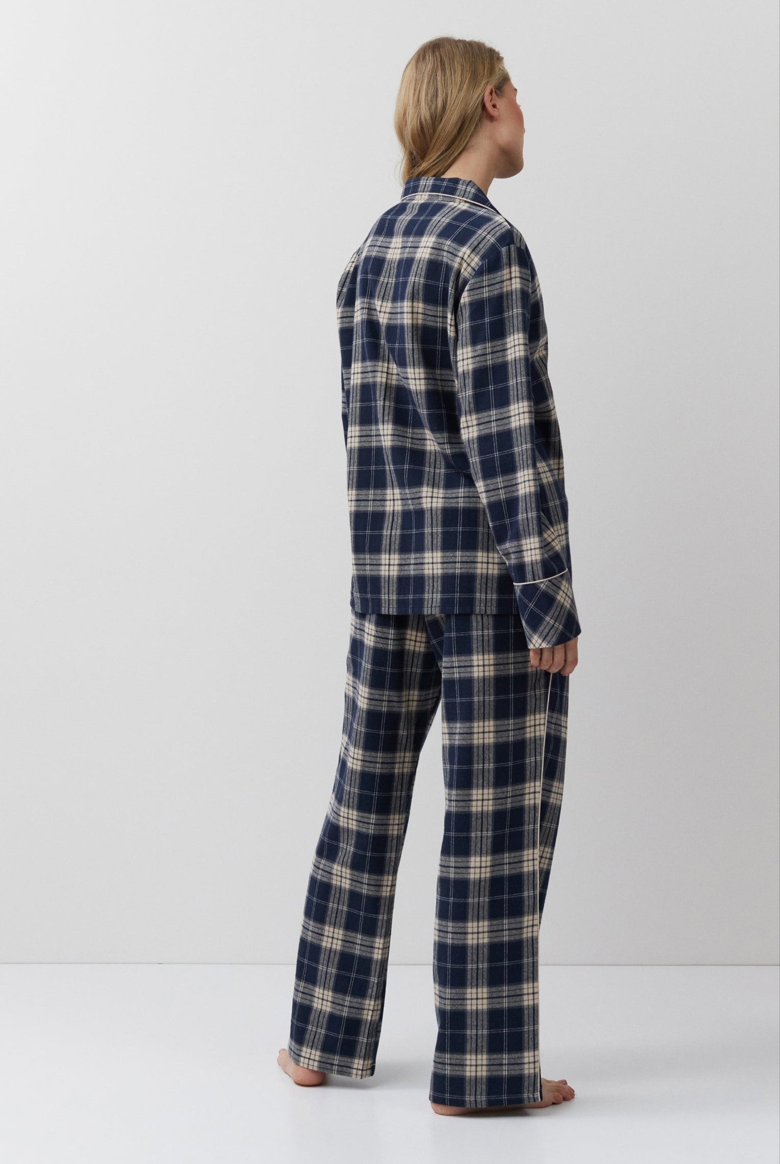 Person wearing a blue and beige plaid pajama set against a white background