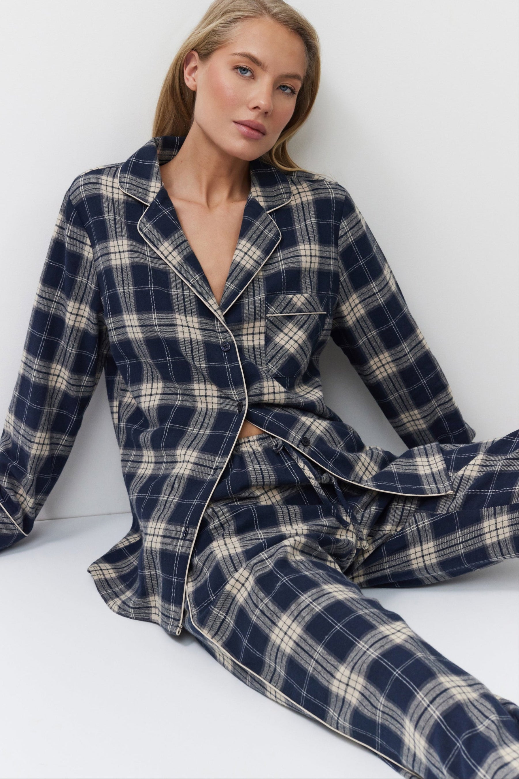 Woman wearing a navy and beige plaid pajama set on a white background