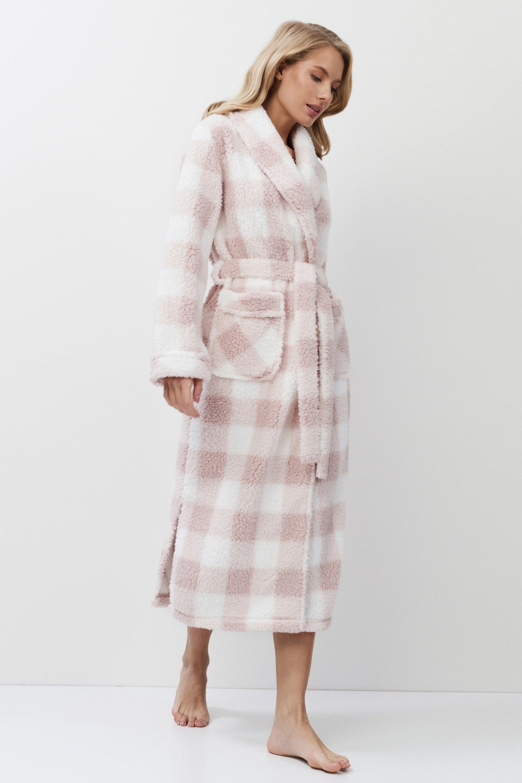 Woman wearing a pink and white checkered bathrobe on a white background