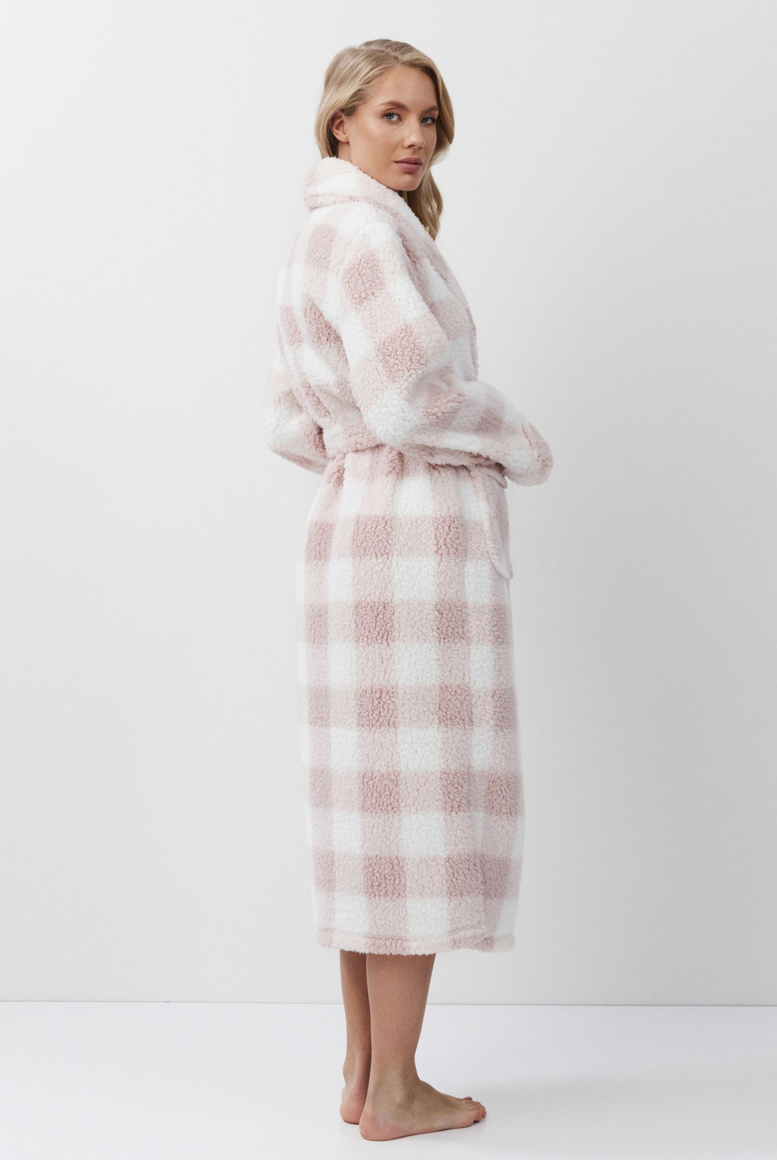 Woman wearing a pink and white checkered bathrobe on a white background