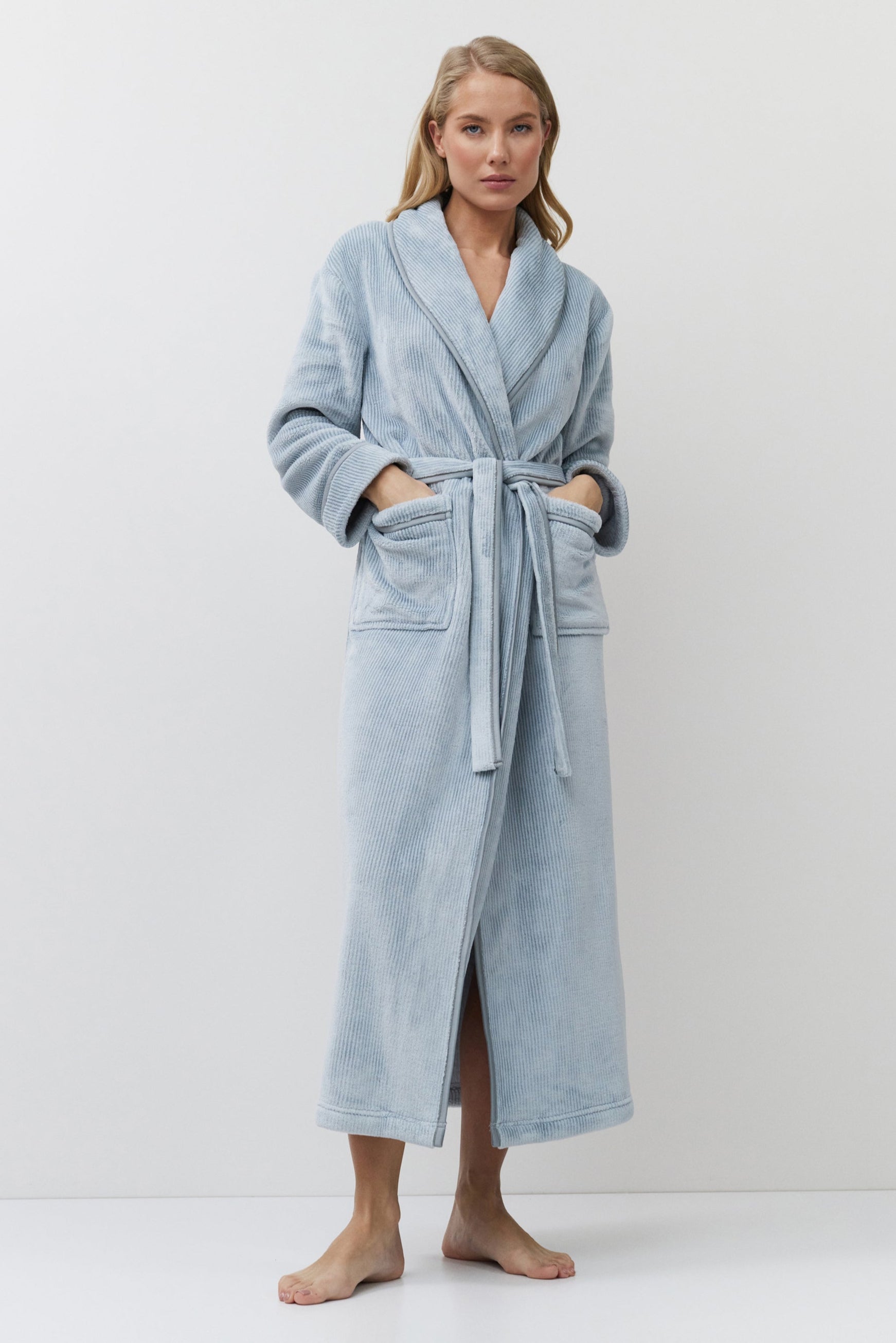 Woman wearing a light blue bathrobe against a white background
