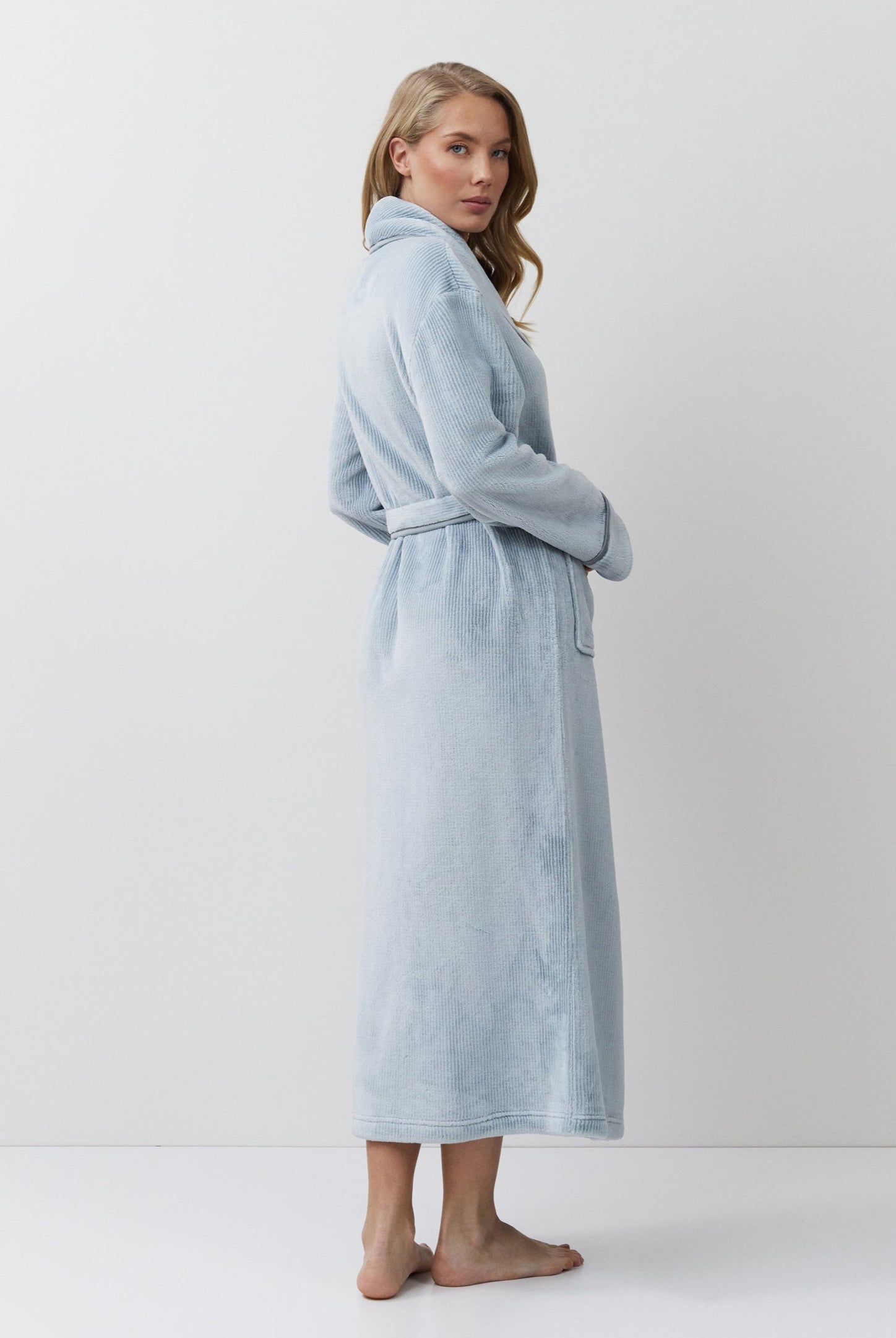 Woman wearing a light blue bathrobe against a white background