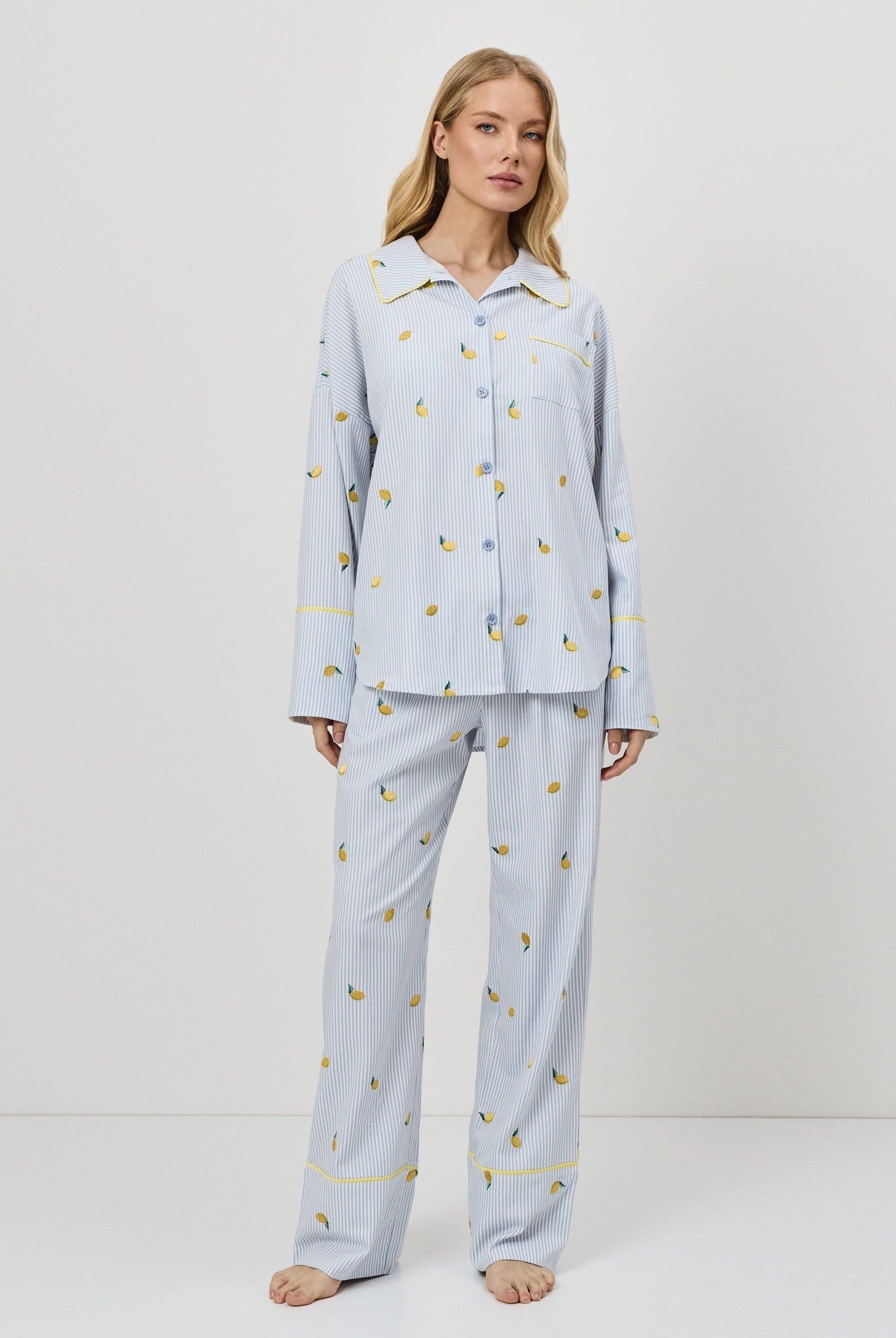 Woman wearing light blue pajamas with a lemon embroideries on a white background