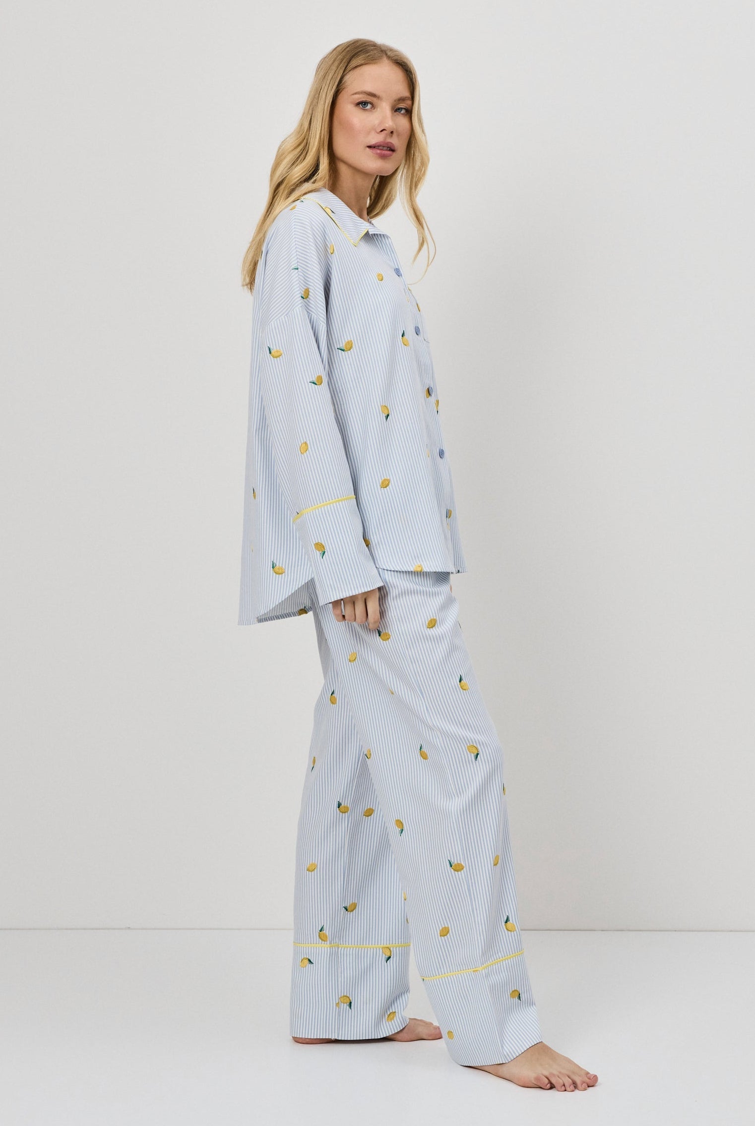 Woman wearing light blue pajamas with a lemon embroideries on a white background