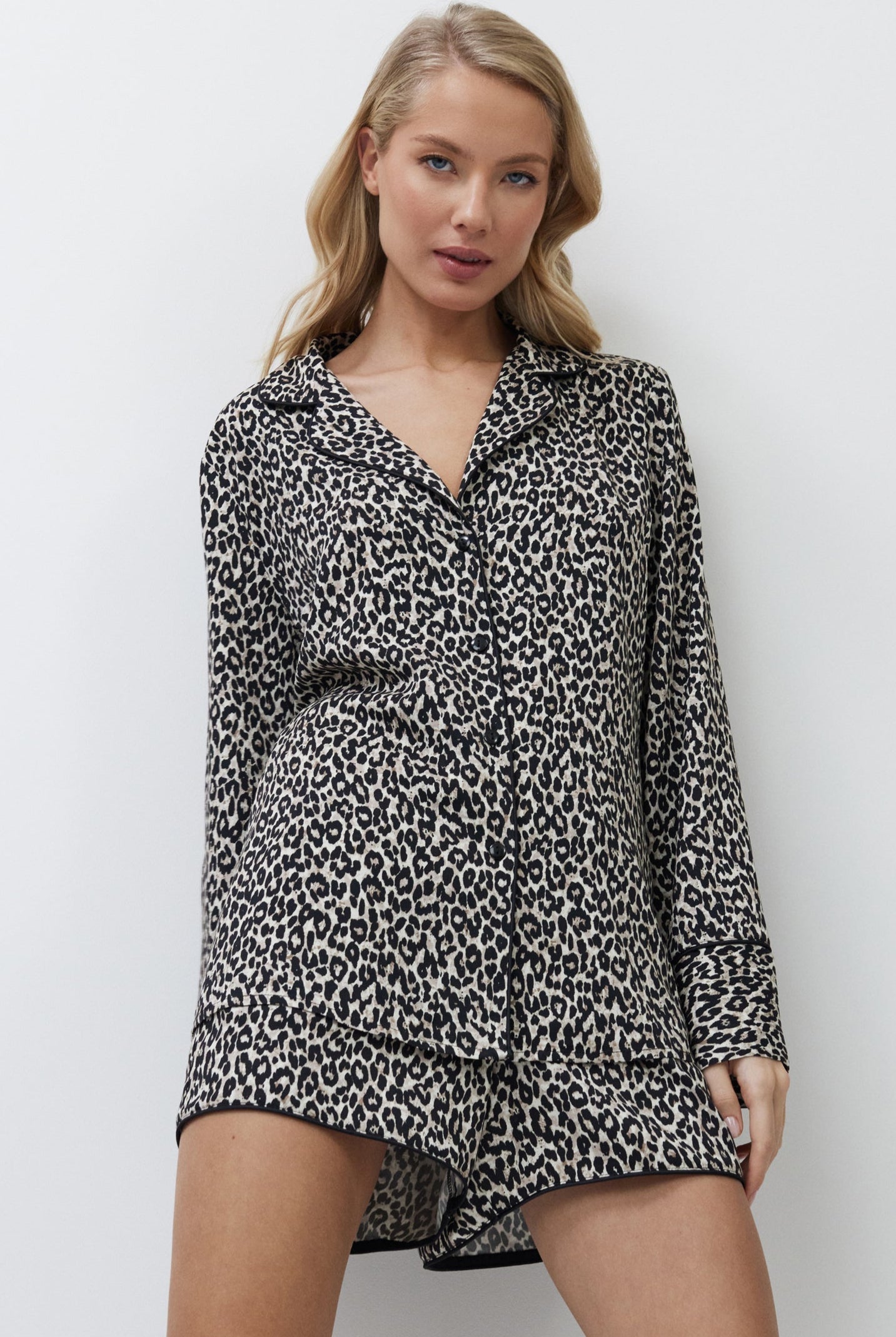 Woman wearing a leopard print pajama set with shorts against a white background