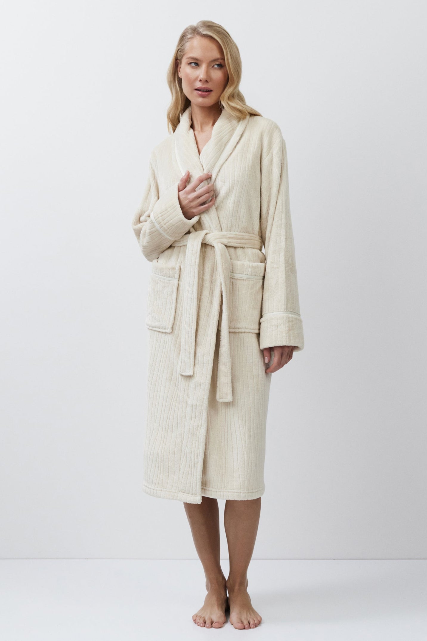 Woman wearing a beige bathrobe against a white background