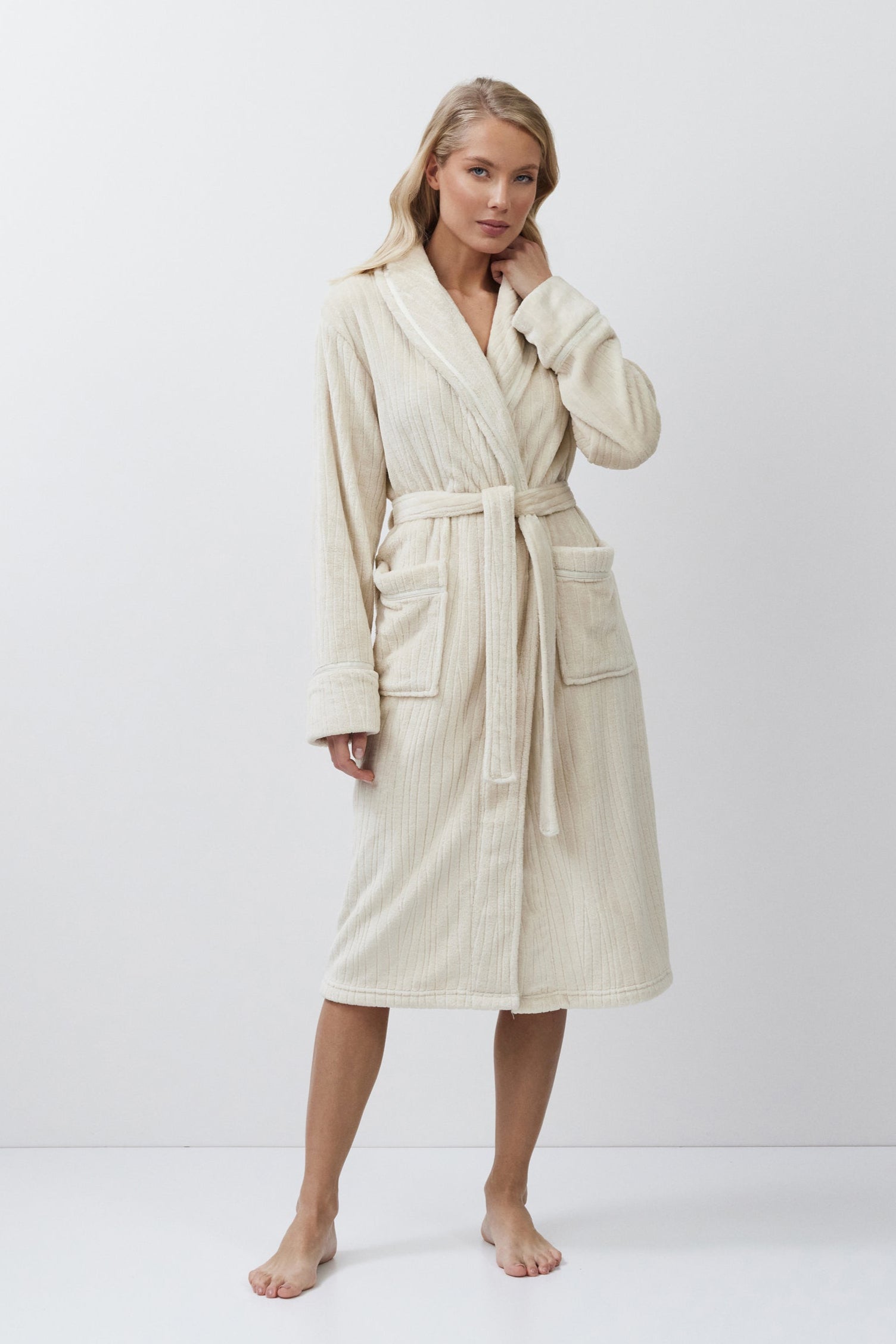 Woman wearing a beige bathrobe against a white background