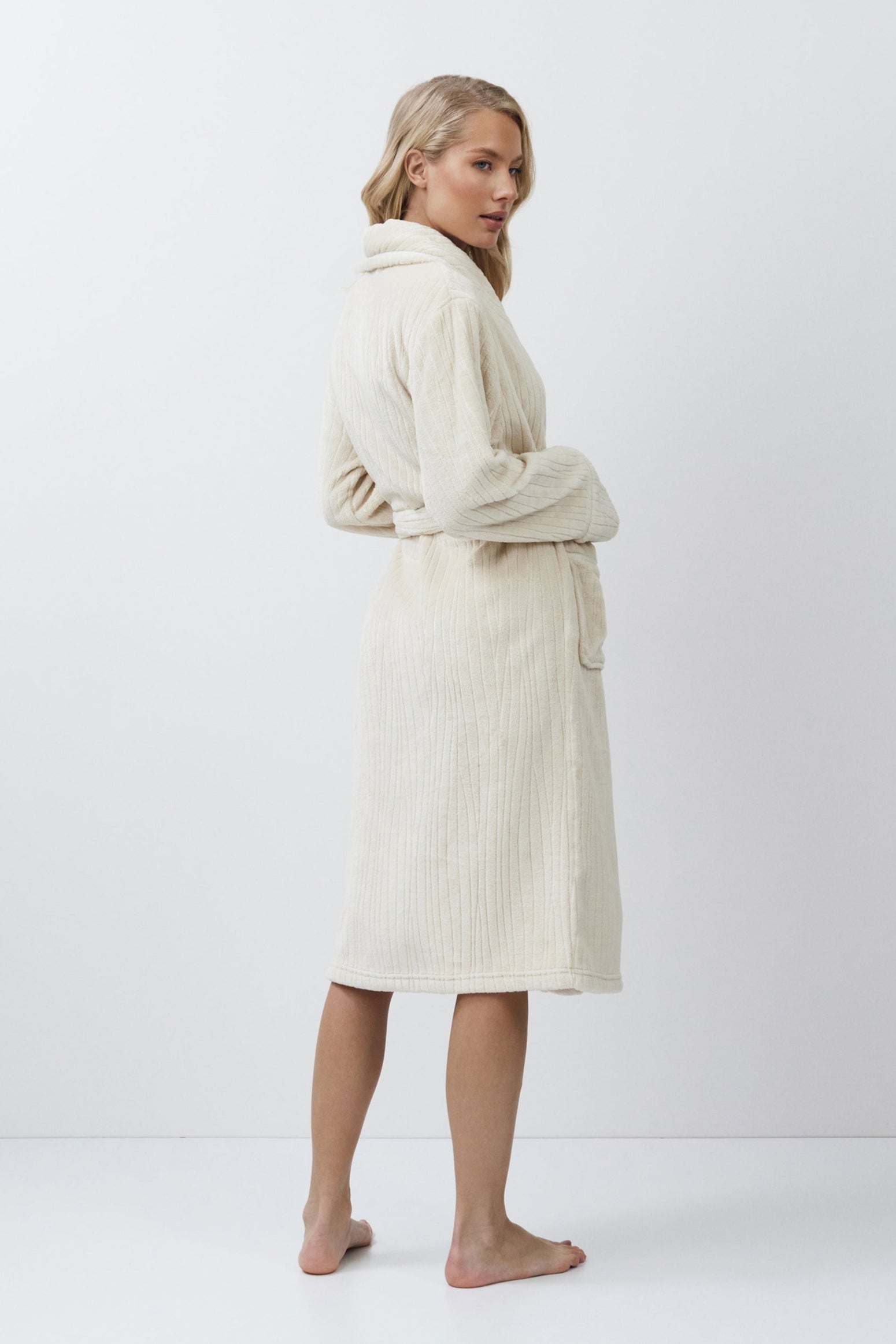 Woman wearing a cream-colored bathrobe against a white background